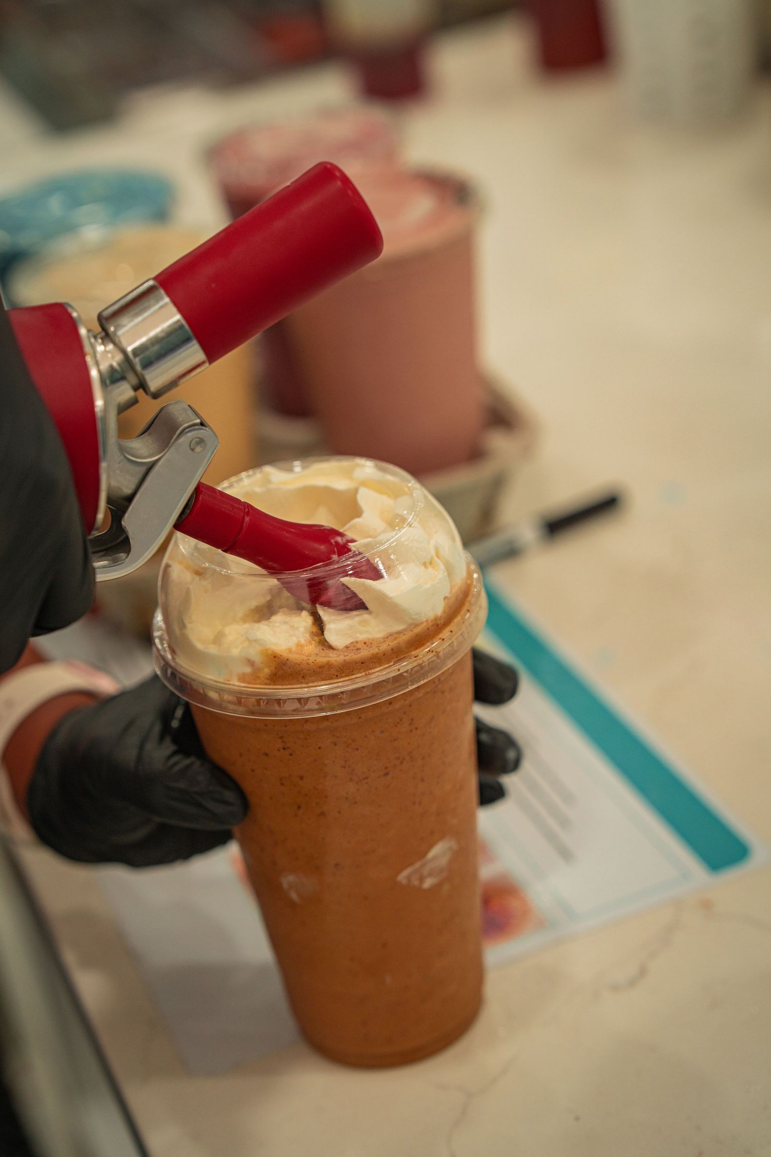 A series of close-up shots showing a red piping bag adding frosting to a chocolate mousse dessert in a glass jar.