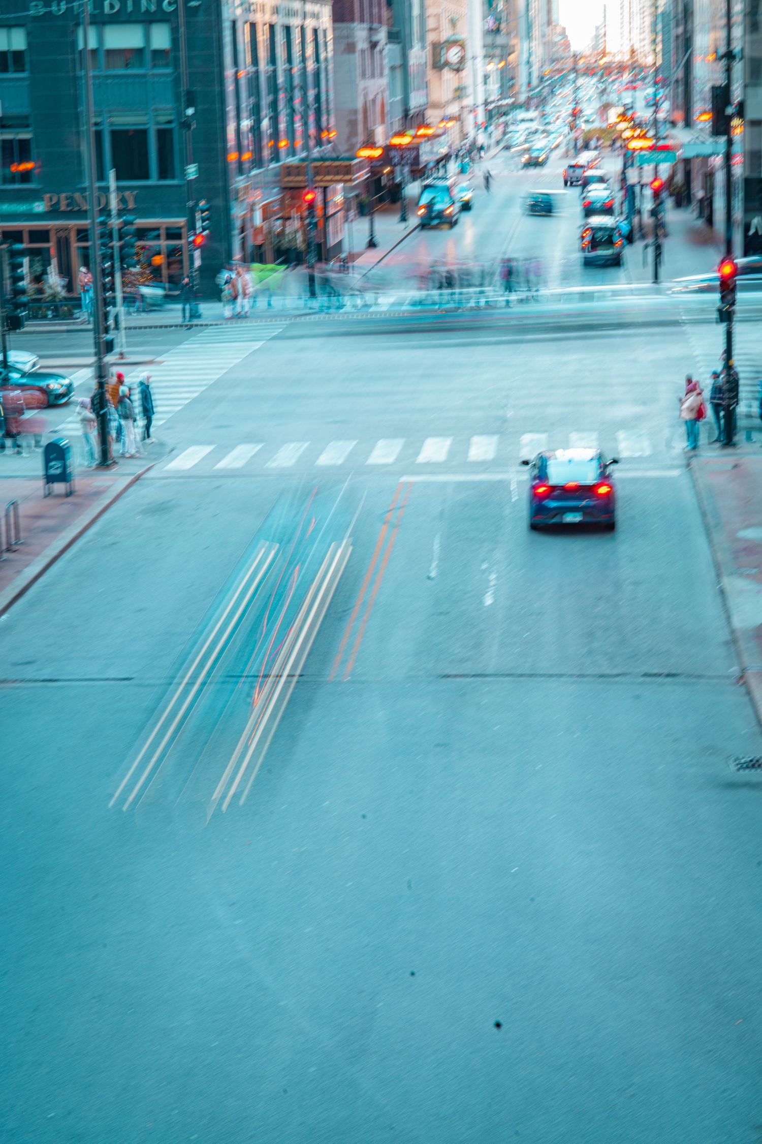 Time-lapse sequence of an urban intersection with cars and pedestrians moving through a city street in blue tones.