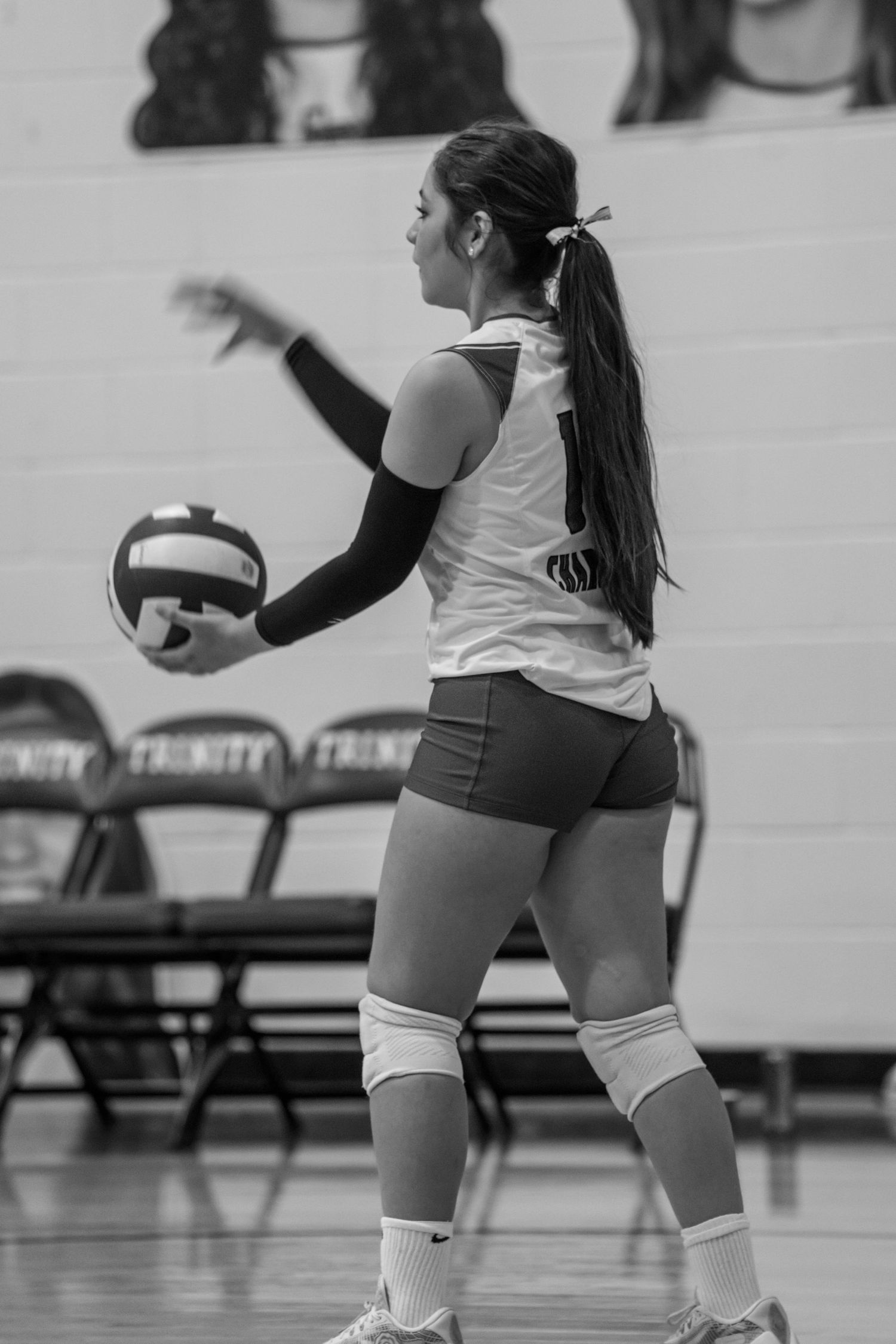 Volleyball players in action during a match showing defensive positions and knee pads in a black and white photo.