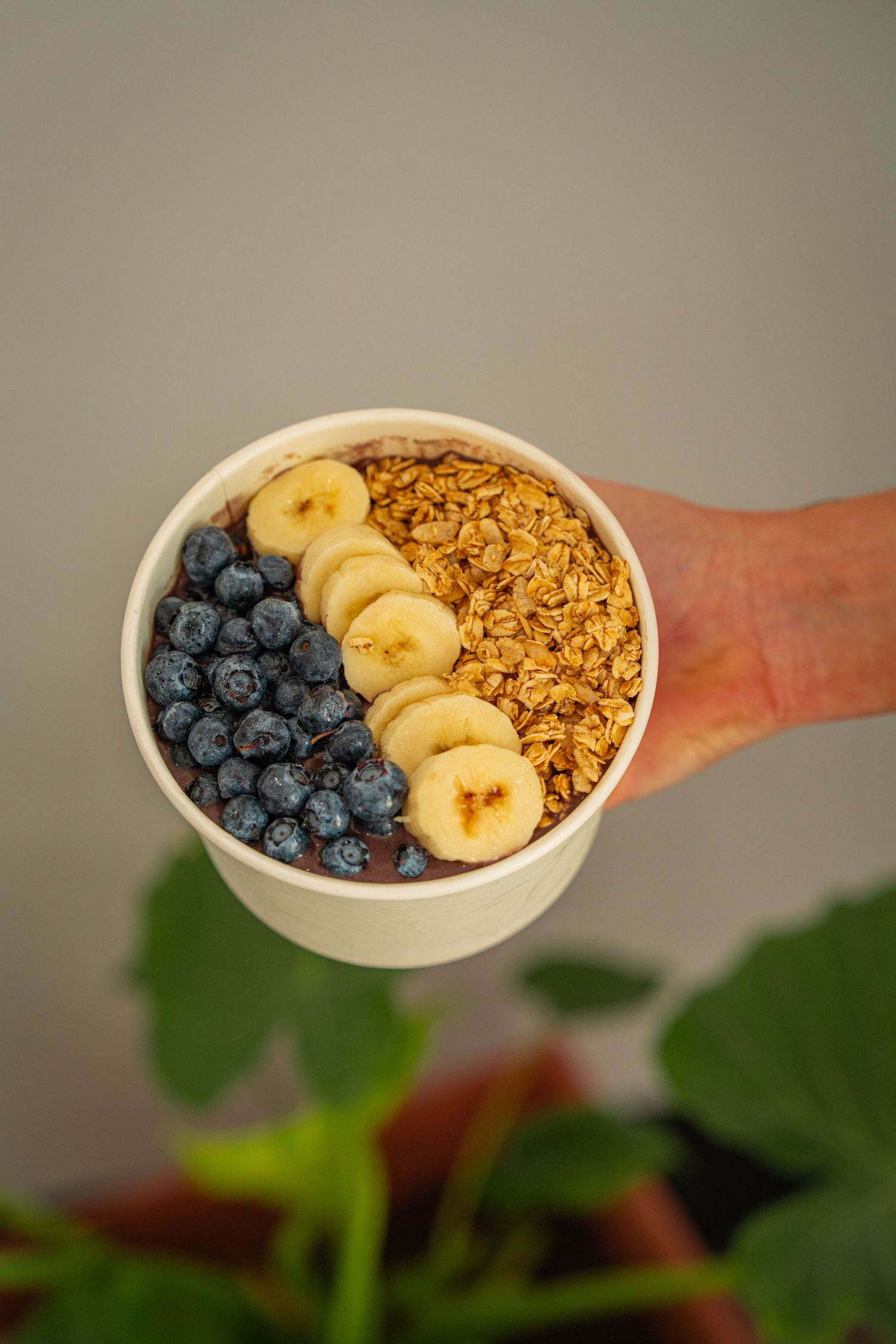 A sequence of photos showing a yogurt bowl being assembled with granola, banana slices, and fresh blueberries.