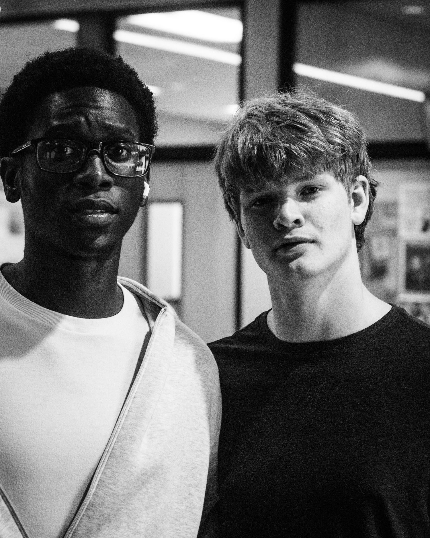 Black and white portrait of two young friends standing together indoors.