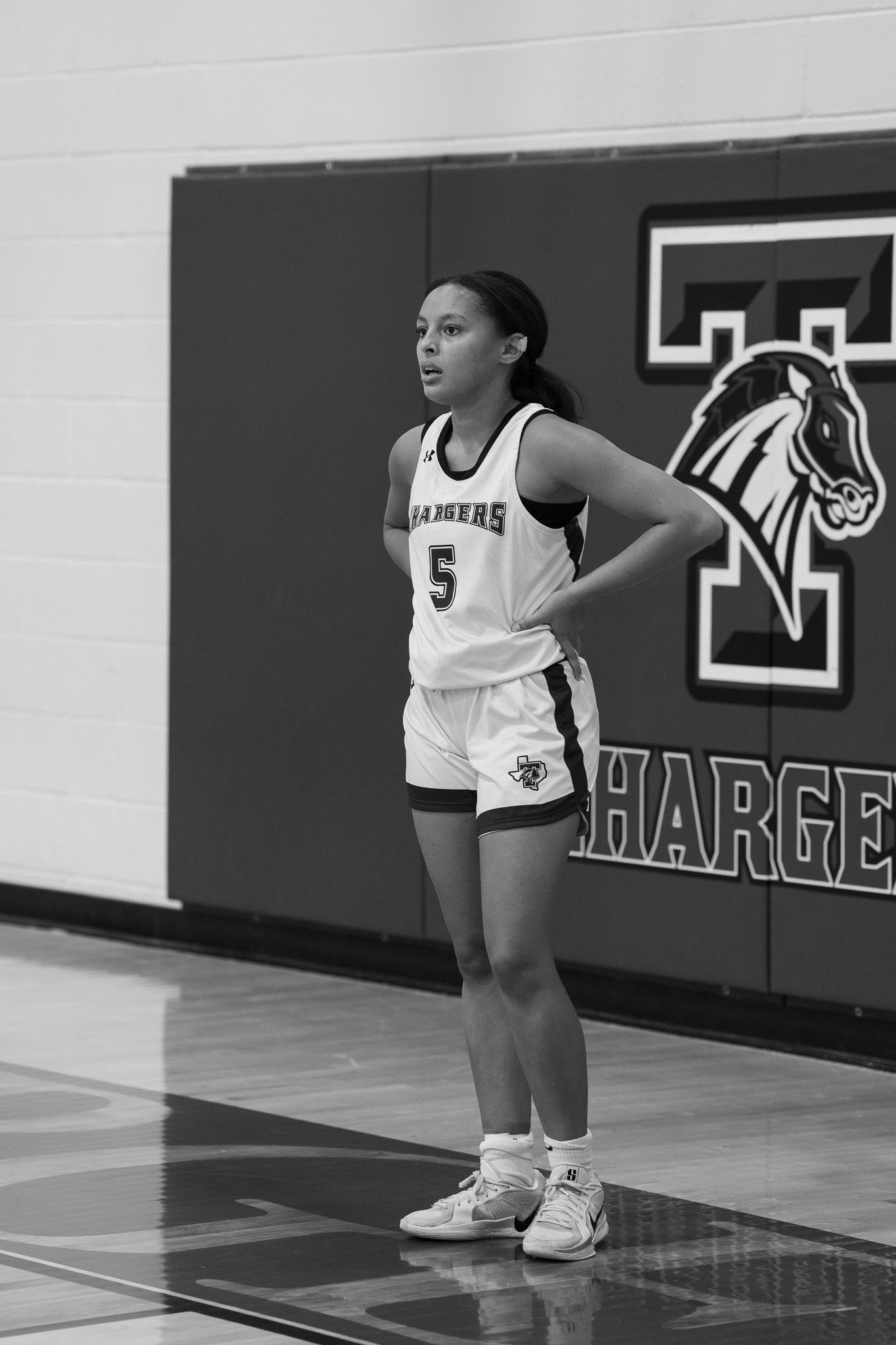 Basketball players stand on a glossy court with Charger signage visible on the wall.
