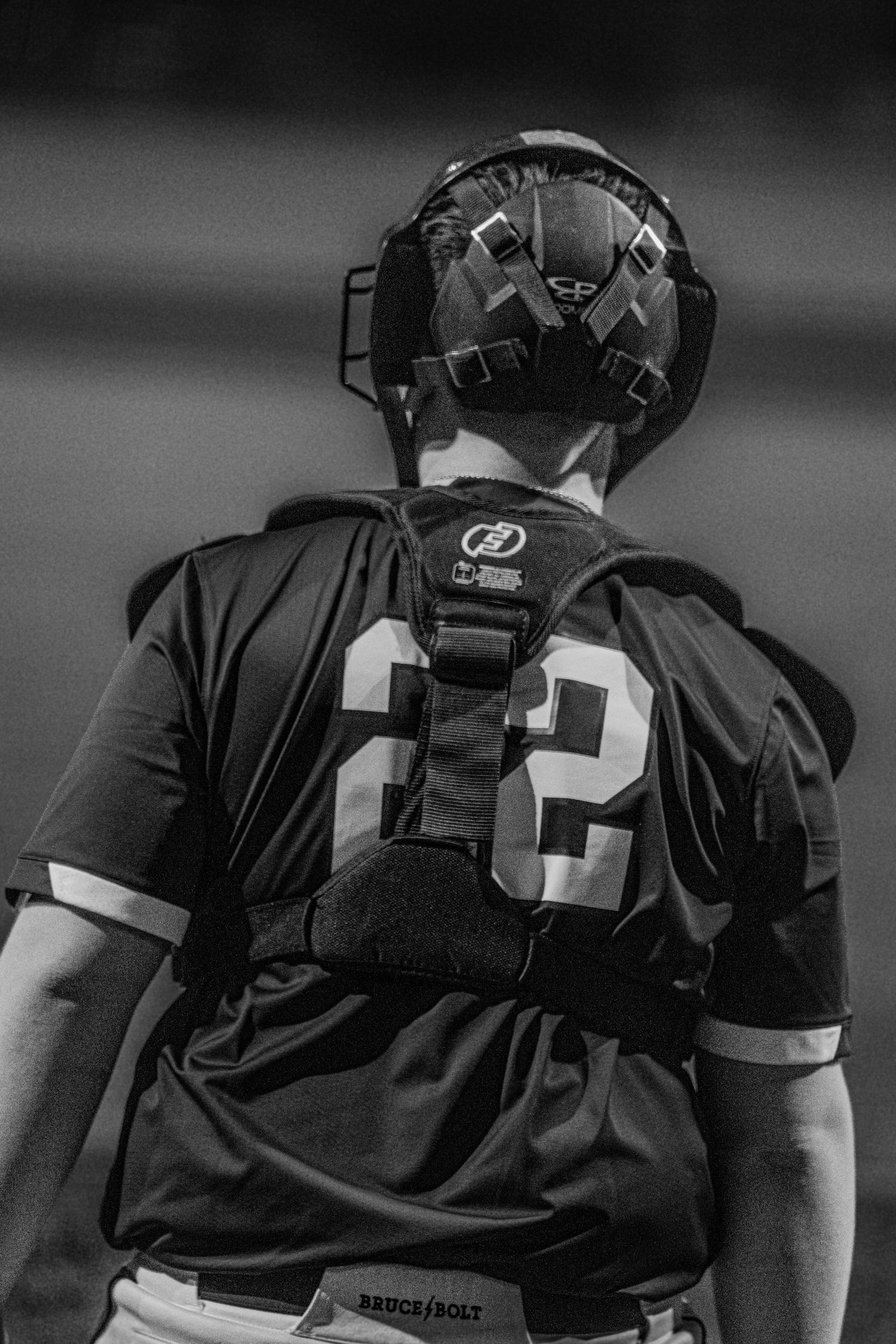 Black and white photo of a baseball catcher wearing jersey number 22 viewed from behind during a game.