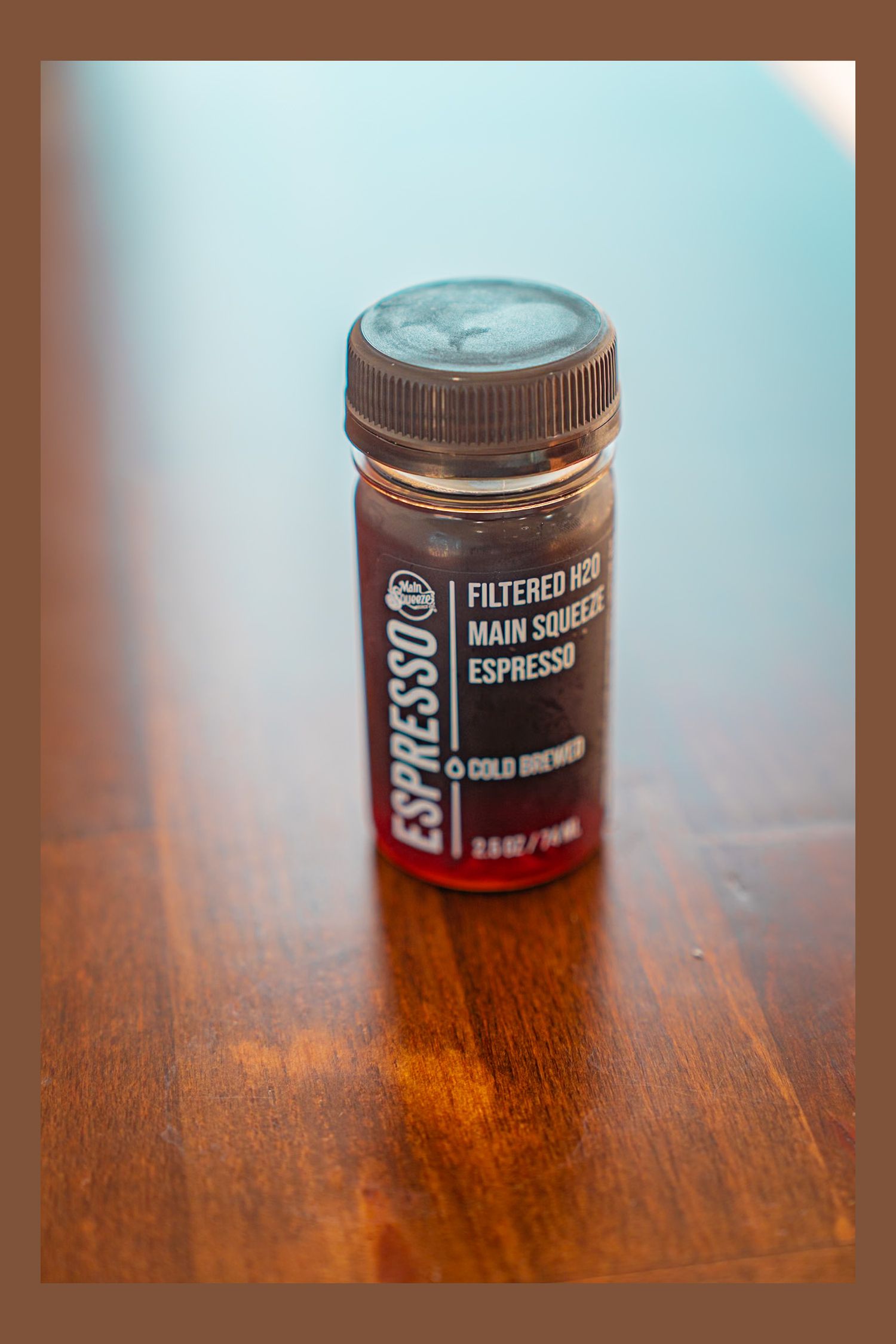 A bottle of Espresso cold brew coffee concentrate sits on a wooden surface with warm lighting.