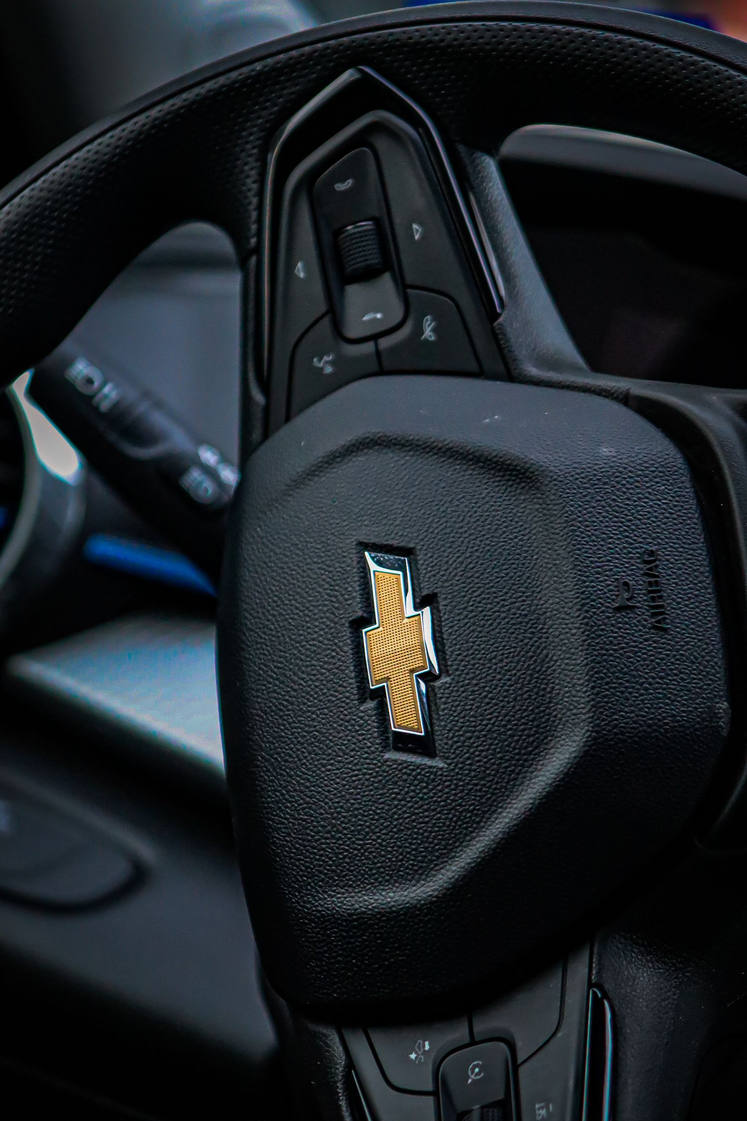 Close-up of a Chevrolet steering wheel showing controls and bowtie emblem.