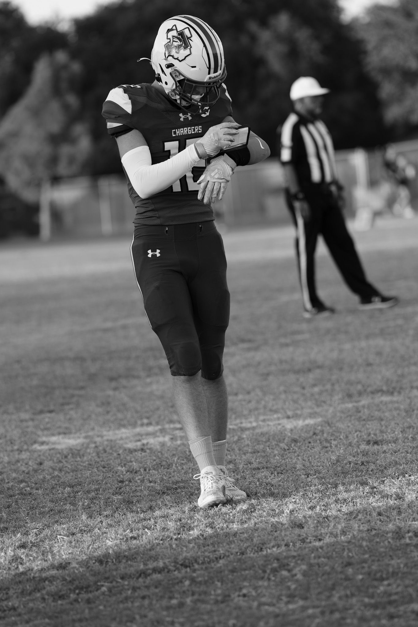 Football player in black Under Armour uniform runs across grassy field during practice.