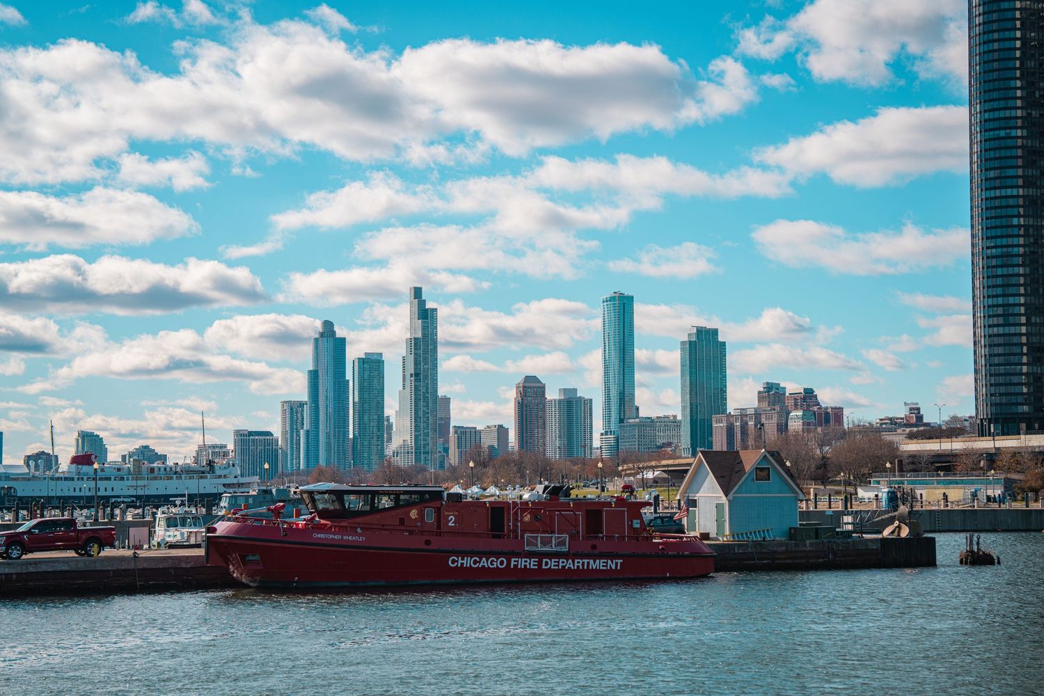 Panoramic view of Chicago skyline with white puffy clouds and blue sky reflecting in Lake Michigan.
