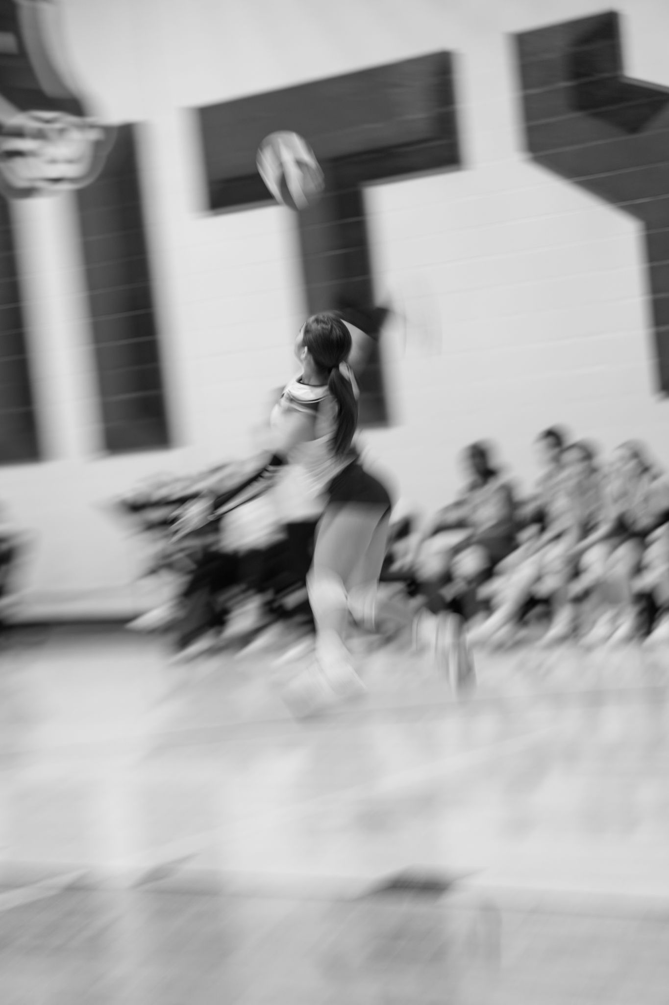 A sequence of blurred motion photographs showing a figure spinning in dance-like movements against a light background.