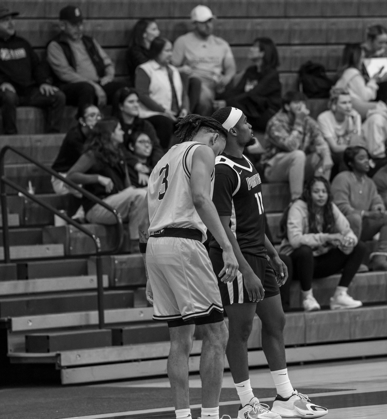 Black and white basketball game action shot showing players in motion during an intense match.