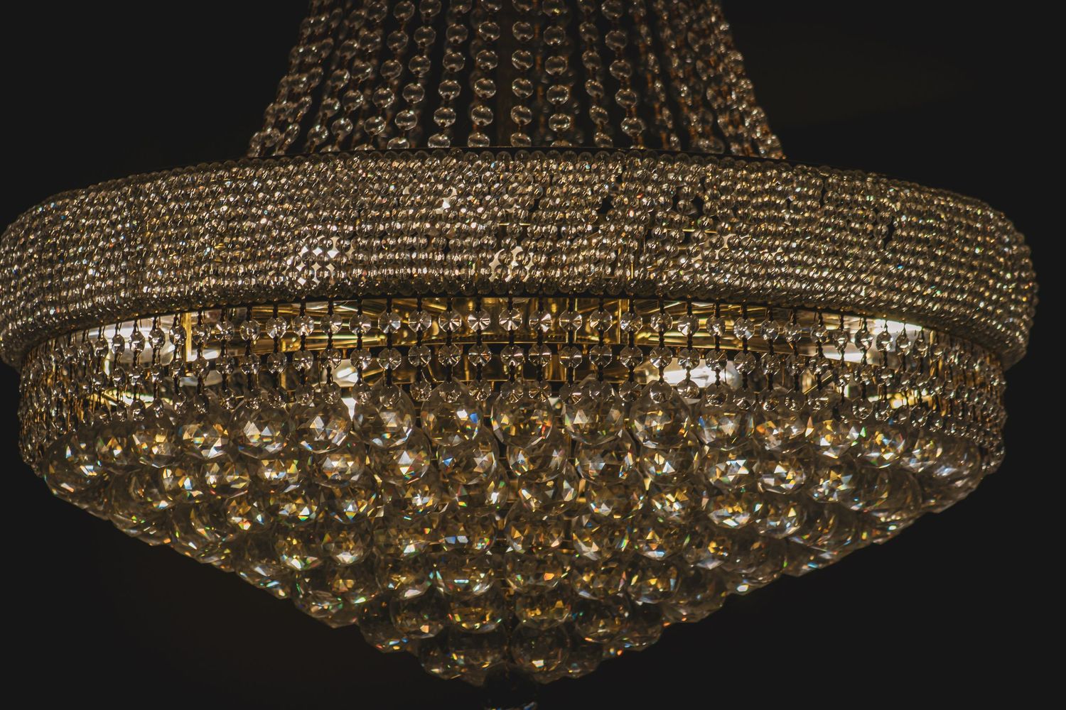 Ornate crystal chandelier with golden finish displaying intricate detail and cascading tiers of glass beads.