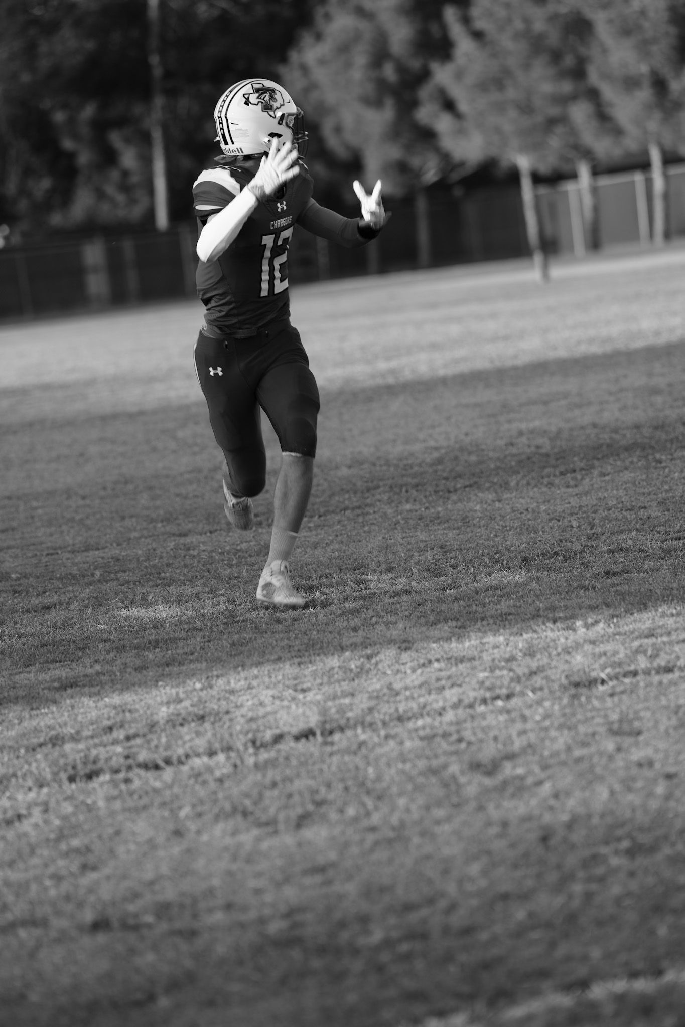 Black and white action shot of football player running across field during practice.