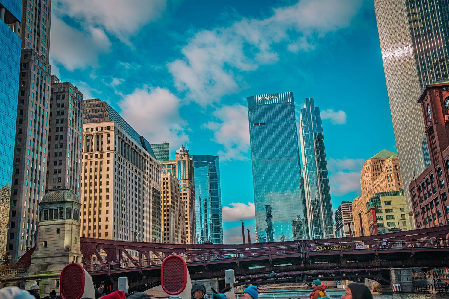 Chicago River view with skyscrapers and bridge against bright blue sky with fluffy clouds in downtown Chicago.