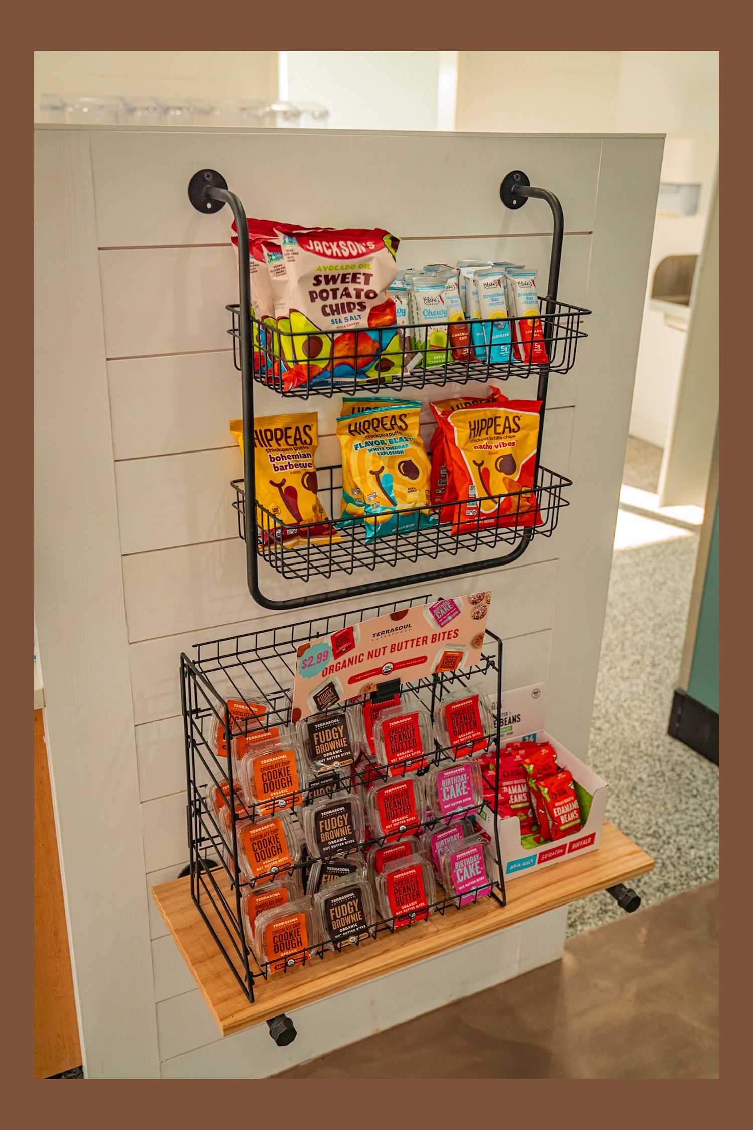 A series of wire snack racks mounted on a wall displaying colorful bags of chips and snacks in an organized manner.