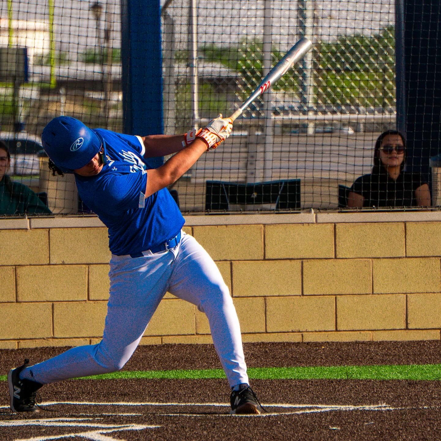 Baseball player in blue jersey swinging bat during game with intense focus.