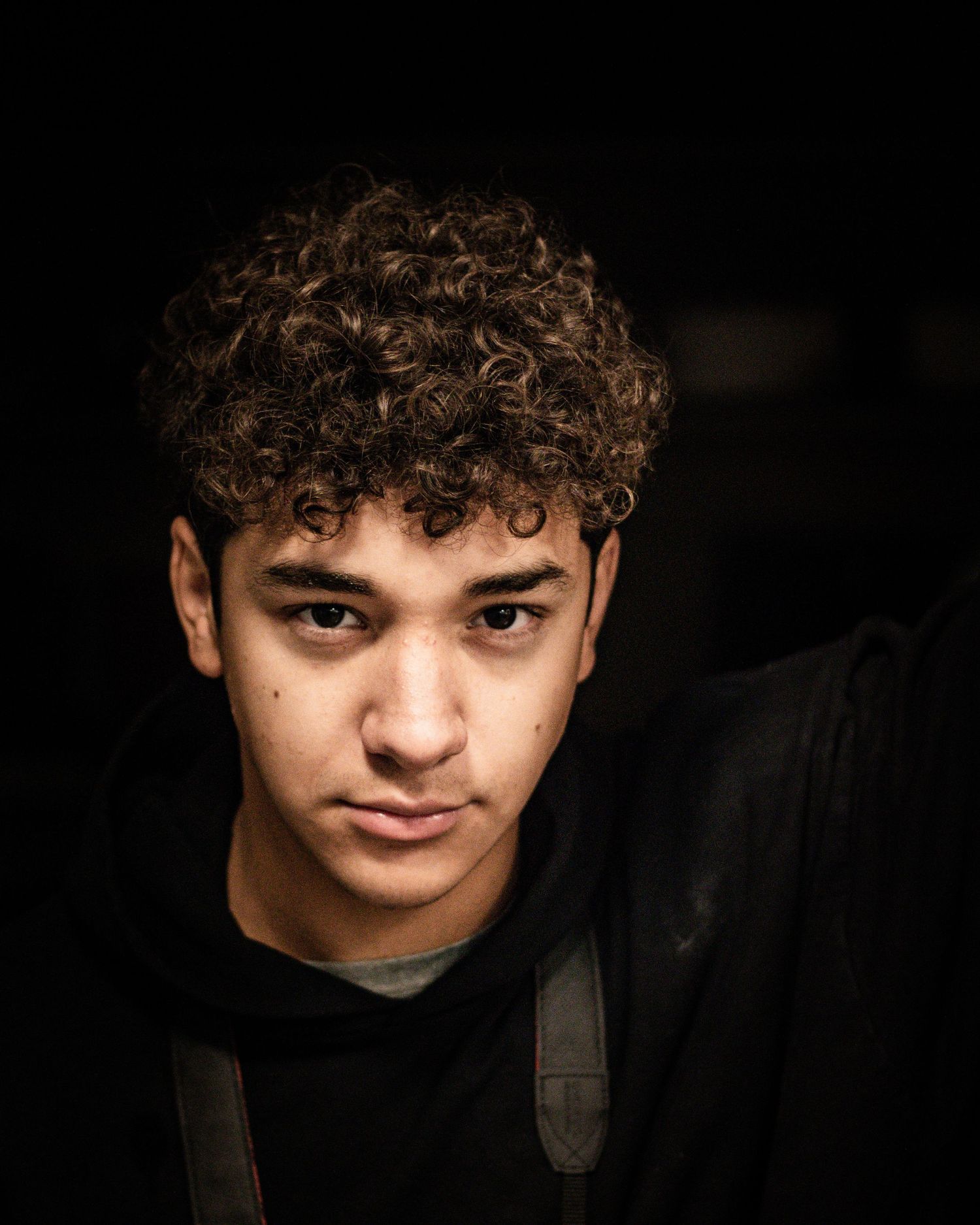Dramatic low-key portrait with moody lighting against dark background.