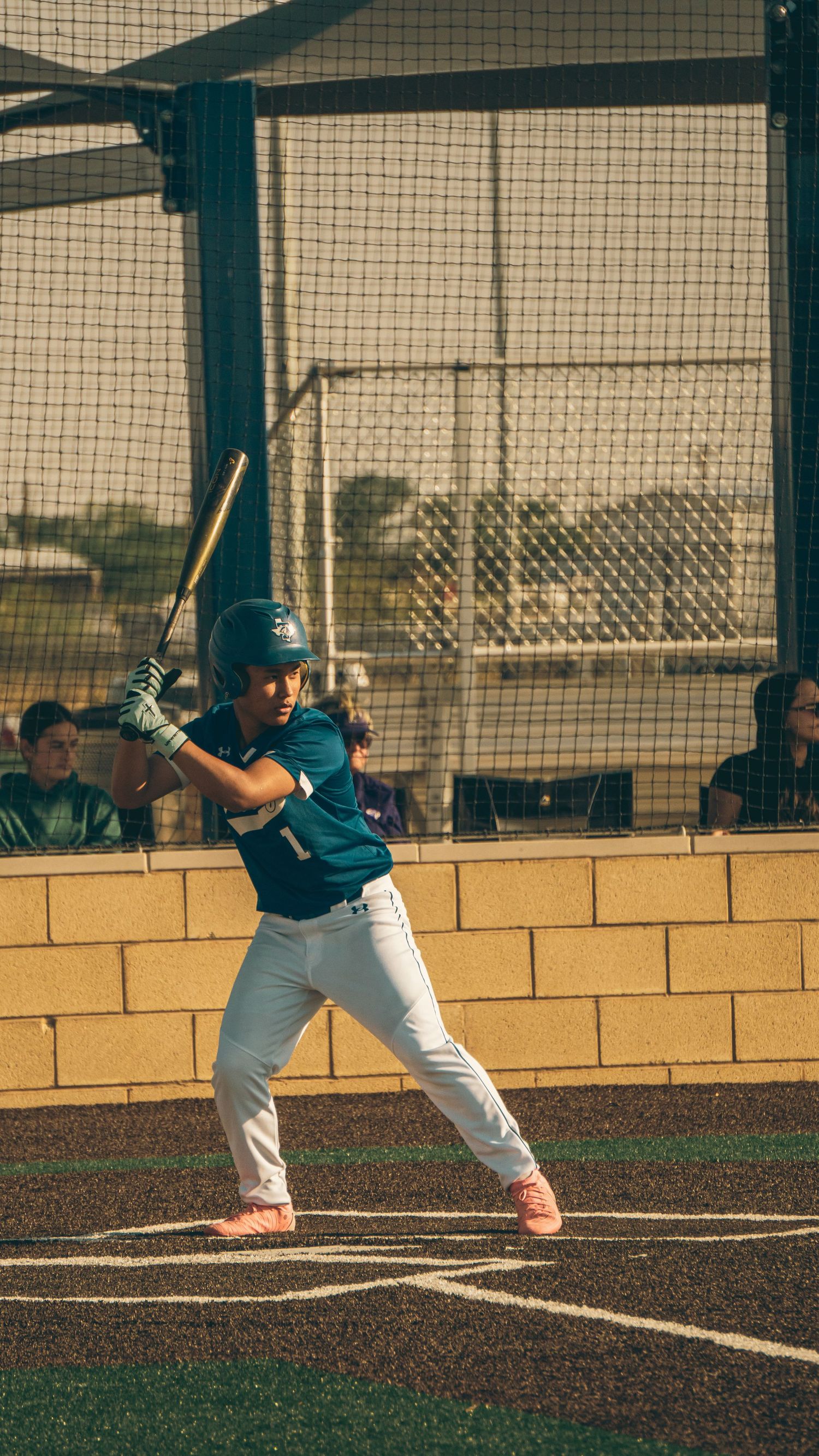 Young baseball player in teal uniform stands in batting stance at home plate during practice.