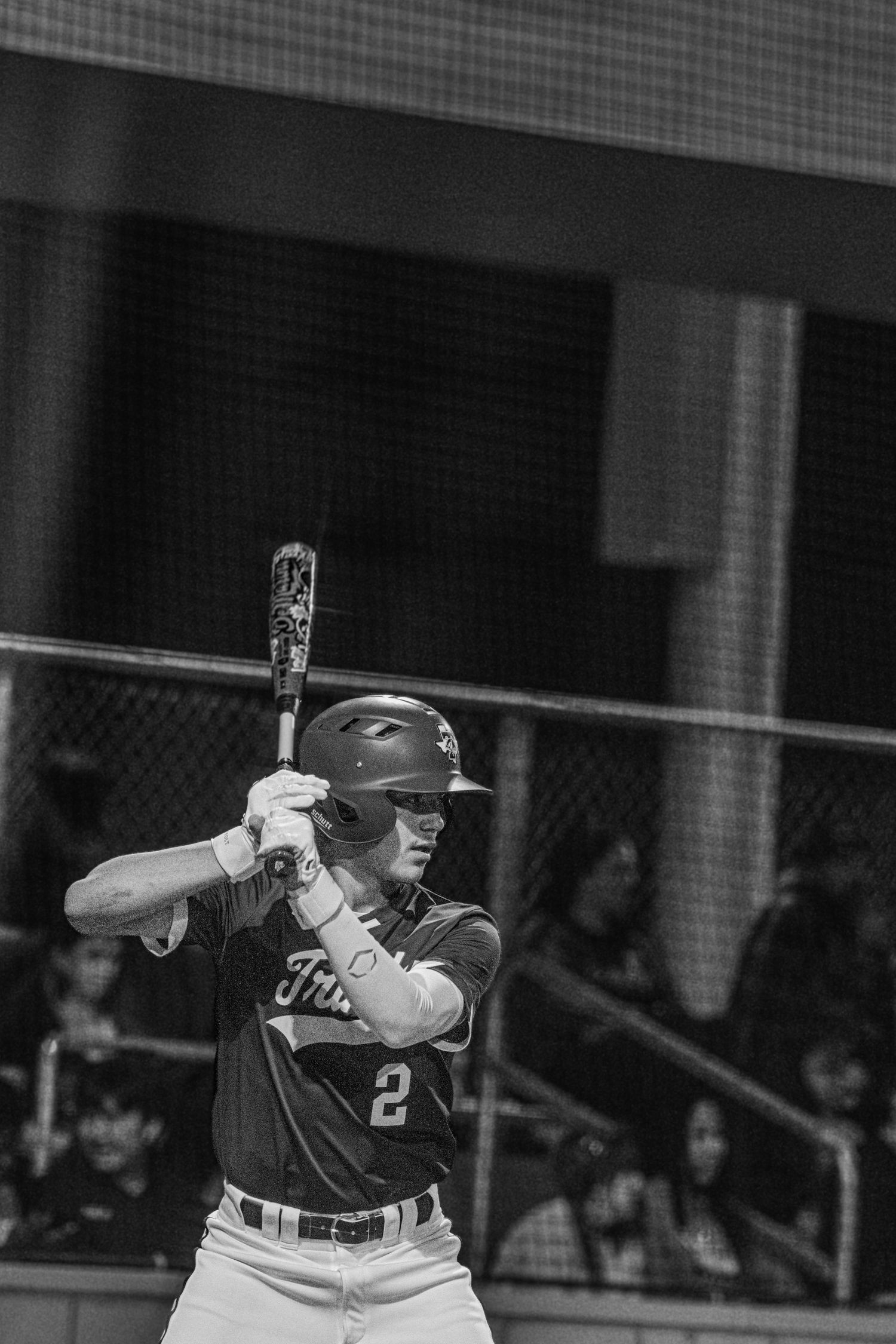 A baseball player in a white uniform swings a bat during a game, shown in black and white photography.