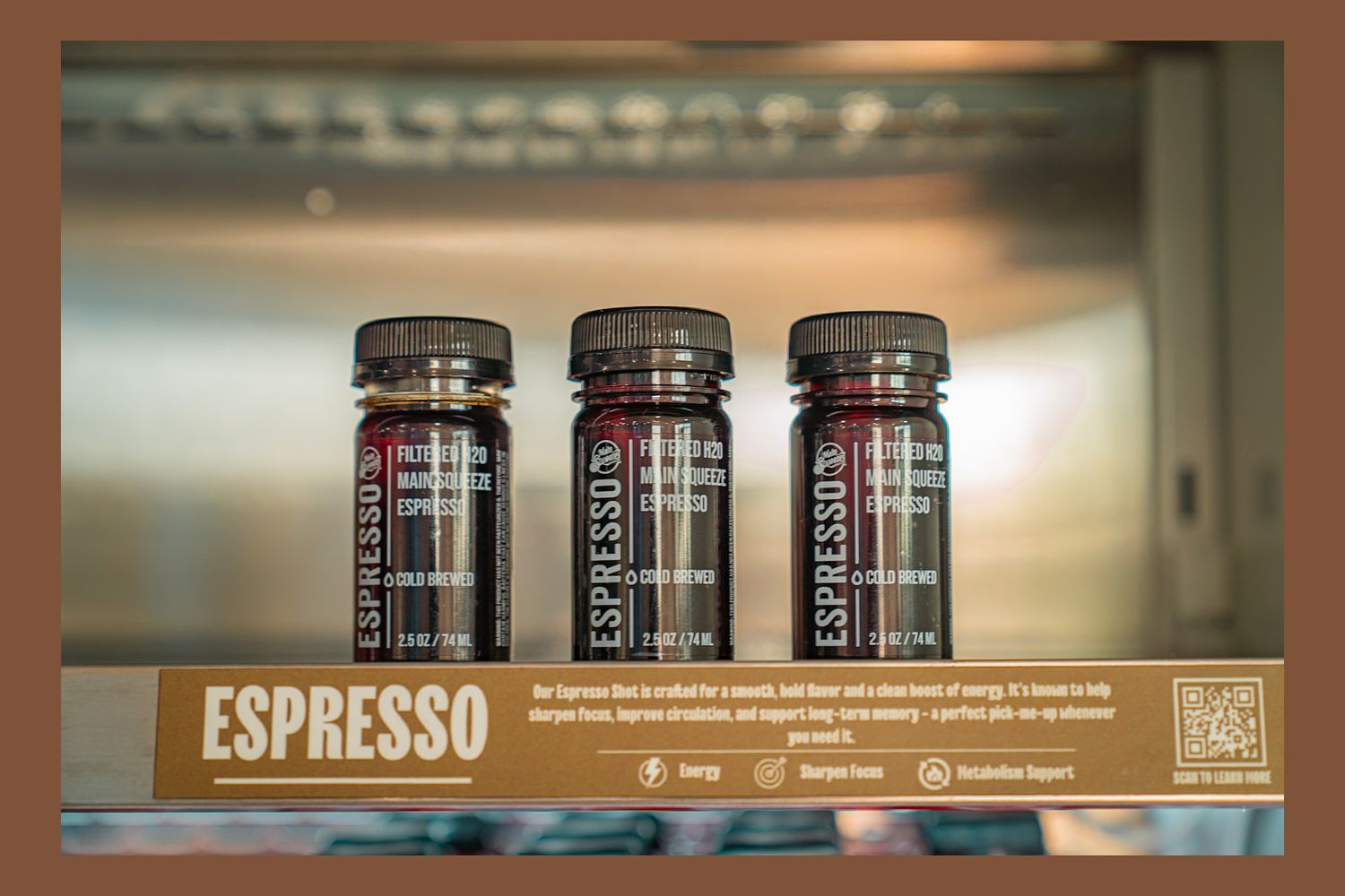 Row of artisanal preserves and espresso jars displayed on wooden shelf in specialty food store.