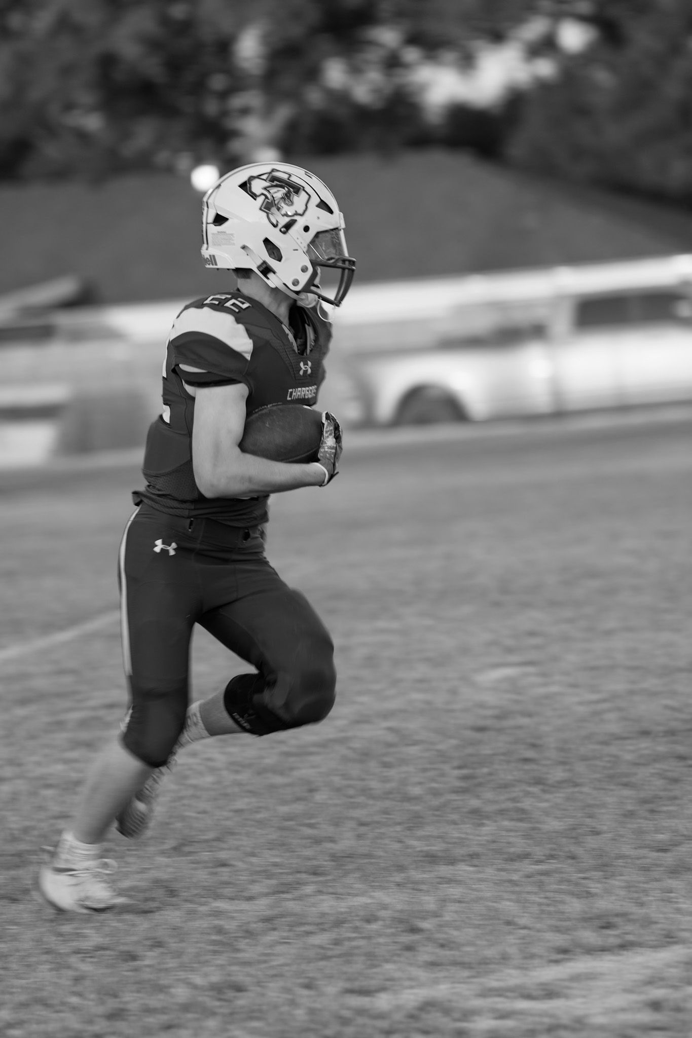 Black and white sequence of football player running and jumping across field in Under Armour uniform.