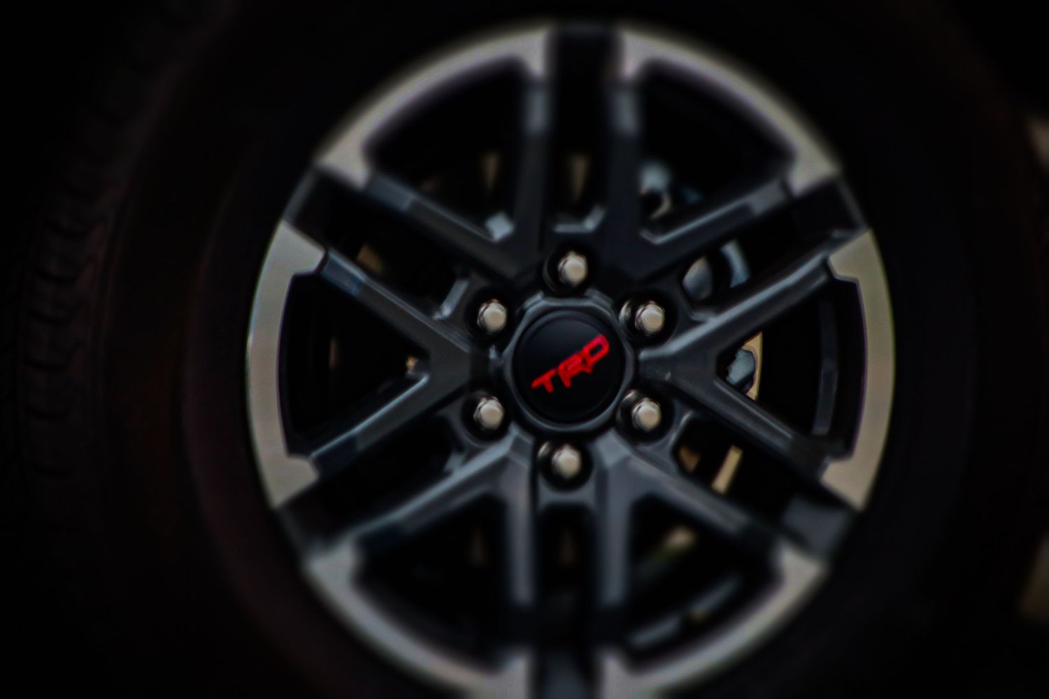 Close-up shot of a dark alloy car wheel with geometric spoke pattern.