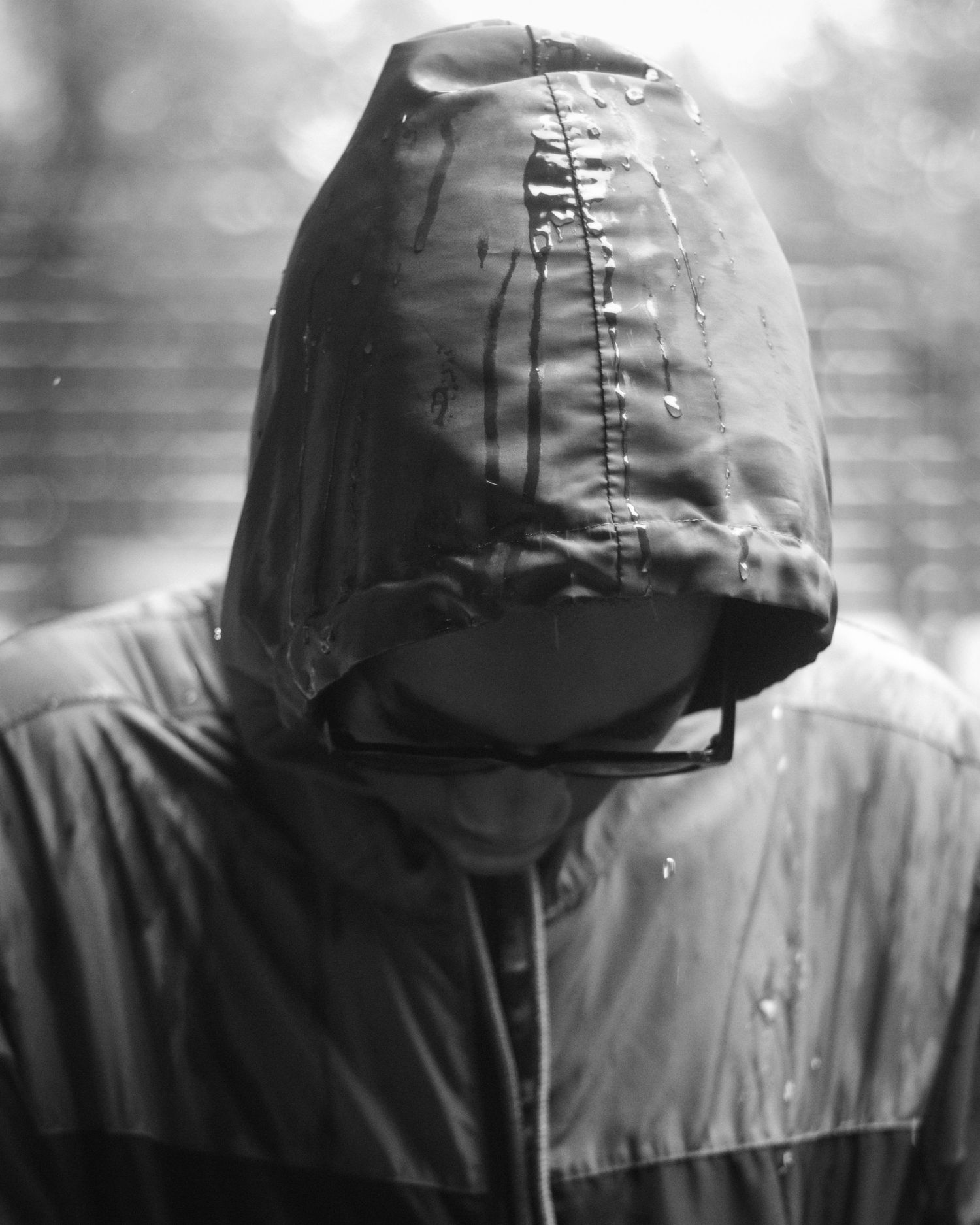 Mysterious black and white portrait of a hooded figure in shadow.