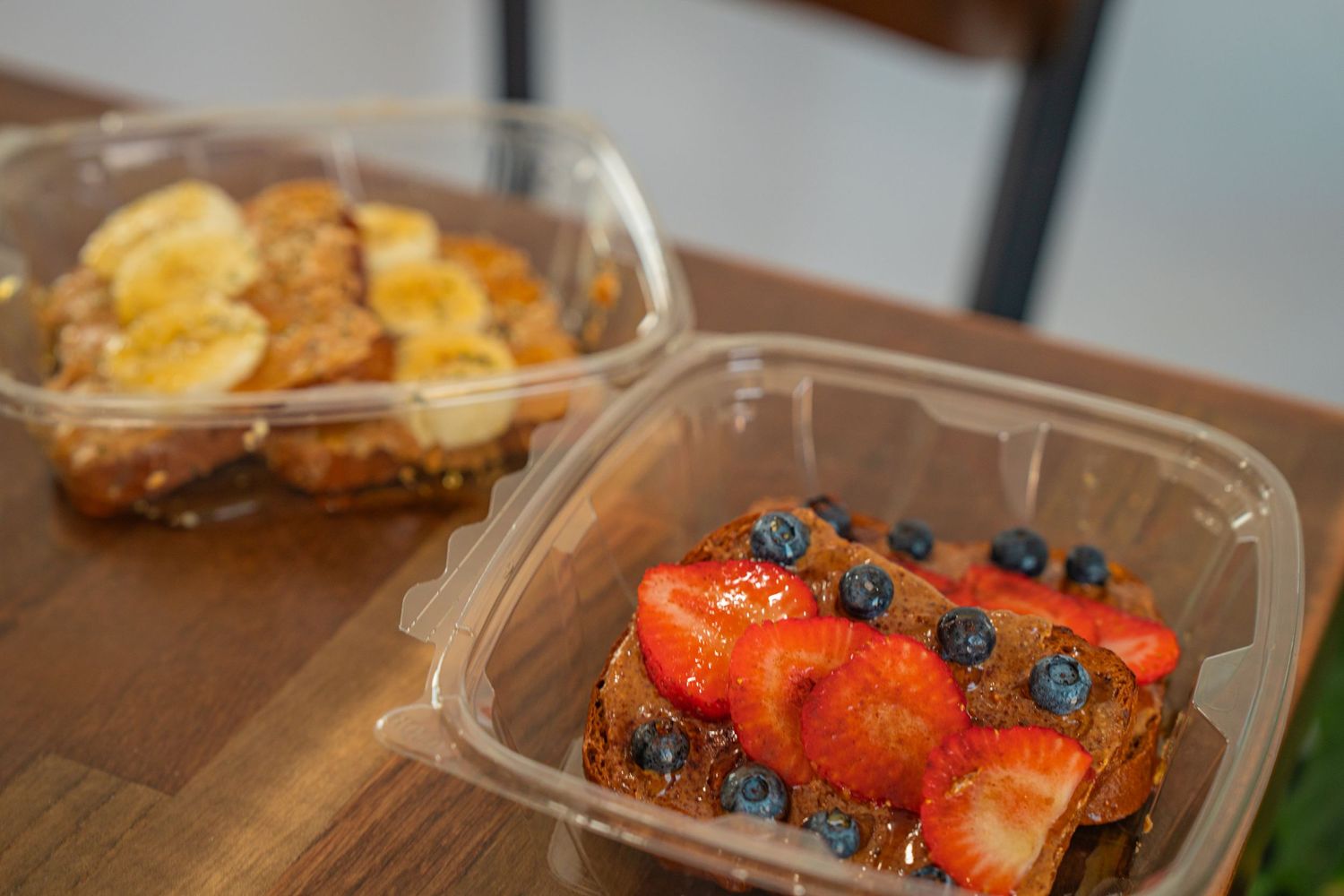 Fresh berries and sliced fruit arranged in plastic containers for healthy meal prep or snacking.