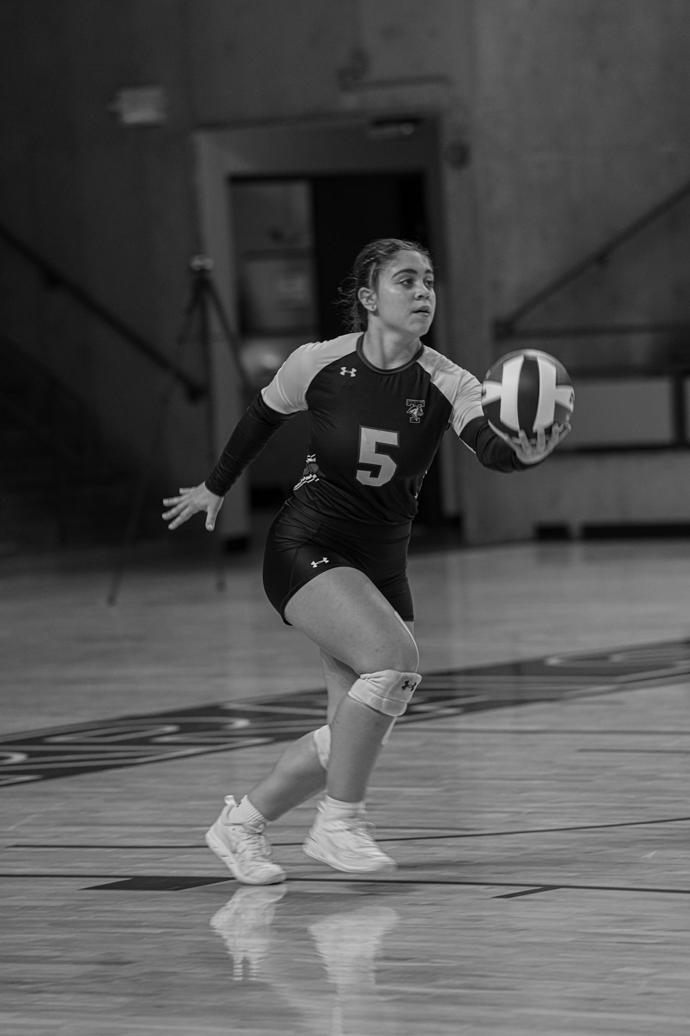 Black and white action sequence showing volleyball player diving to save a ball during an indoor match.