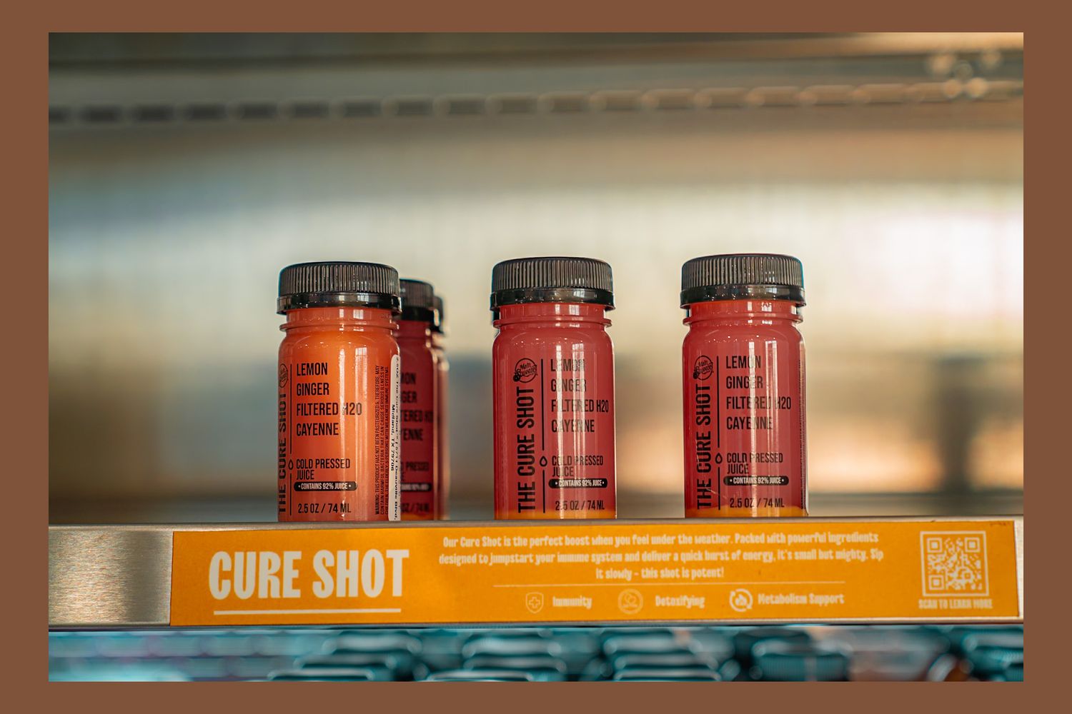 Three red bottled shots lined up on a shelf with an orange 'Cure Shot' label below them.