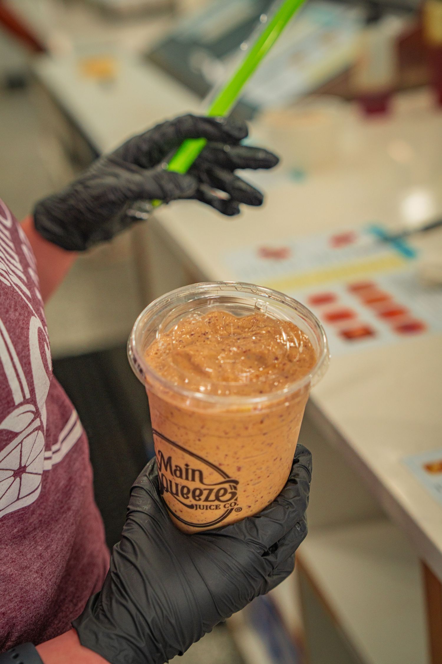 A series of photos showing a smoothie cup being held with black gloves against a white surface.