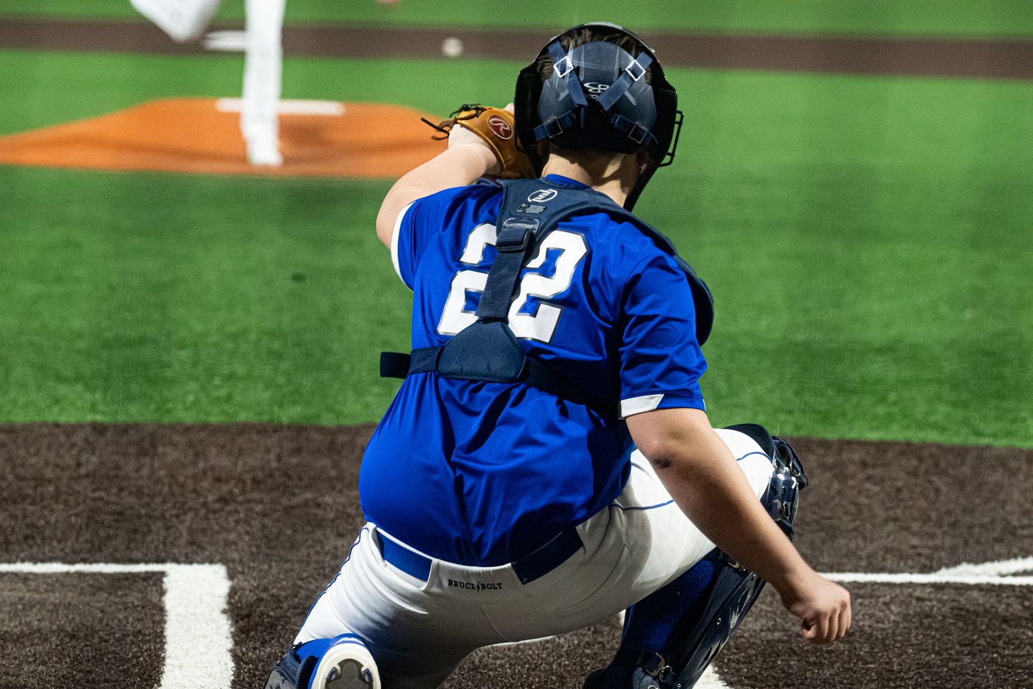 Baseball player in blue uniform slides into base during intense gameplay action on field.