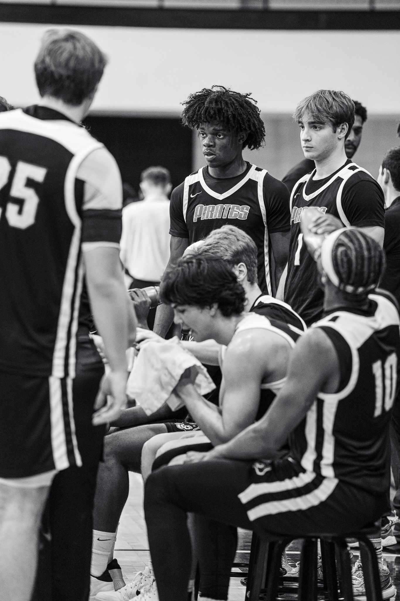 Basketball team sits on the bench during a game wearing black and white uniforms.