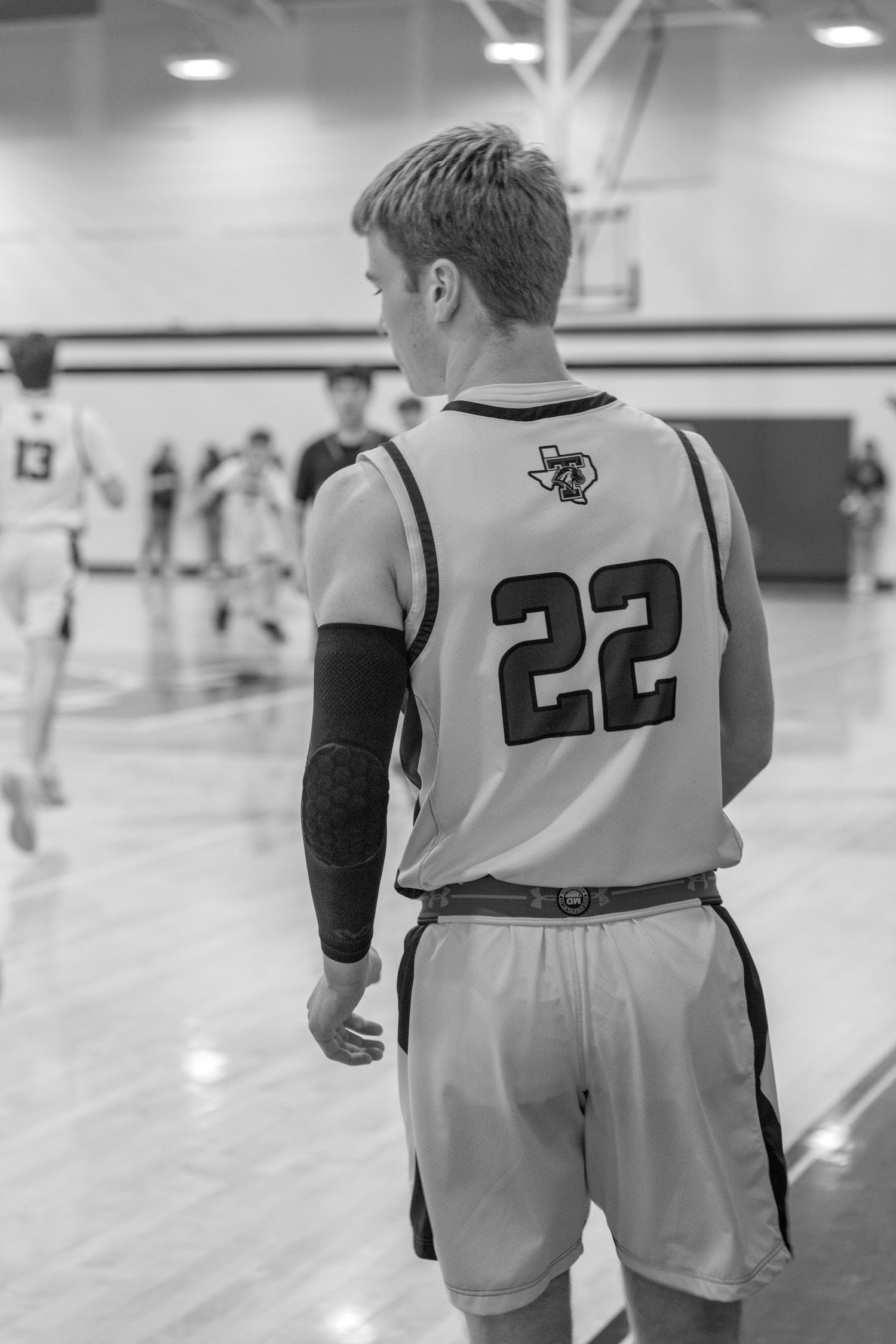 Basketball players in white and black uniforms standing on a court during practice or warmup.