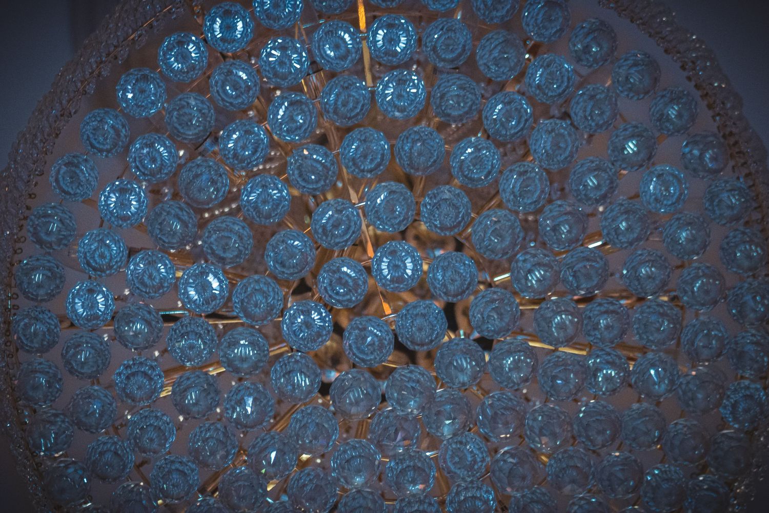 Abstract pattern of illuminated glass crystals creating a blue glowing chandelier effect.