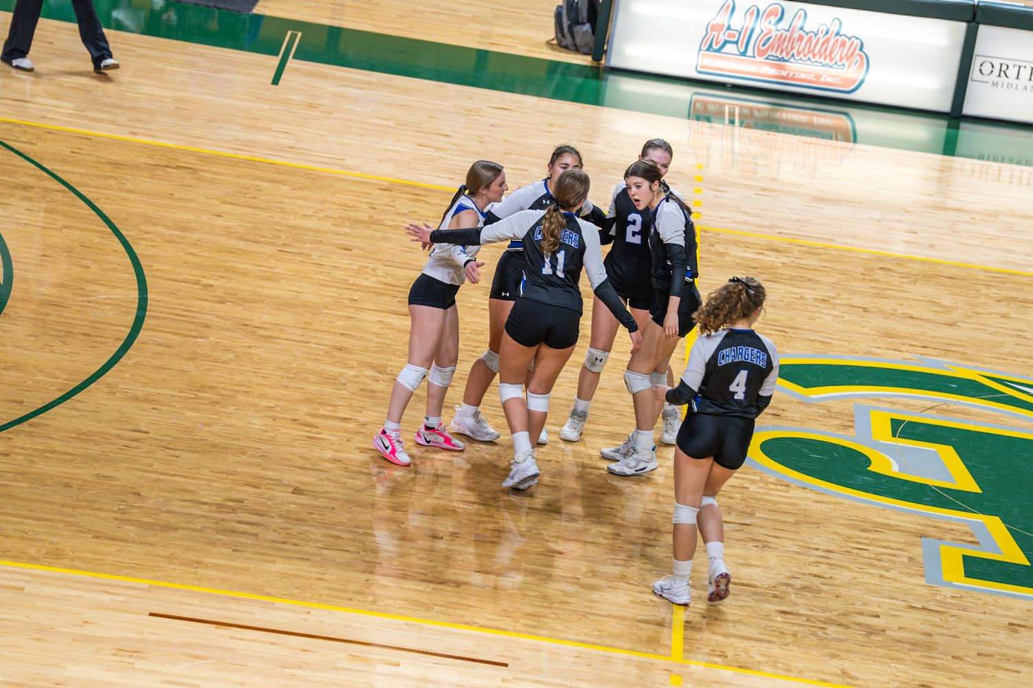 View of a wooden basketball court floor with green painted lines and markings.