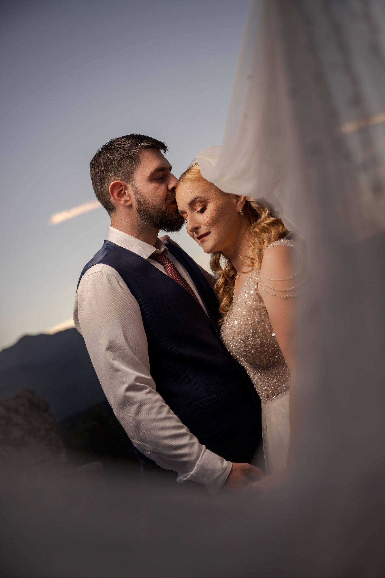 Artful side-lit wedding portraits showing tender moments between a couple against dark background.