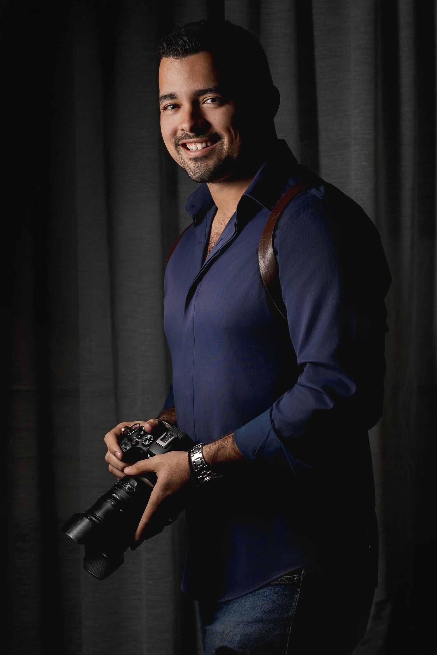 Professional photographer demonstrating camera handling techniques in studio with dramatic lighting.