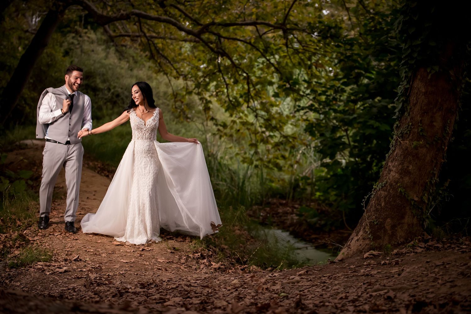 Enchanted woodland wedding portraits under canopy of trees with filtered light.