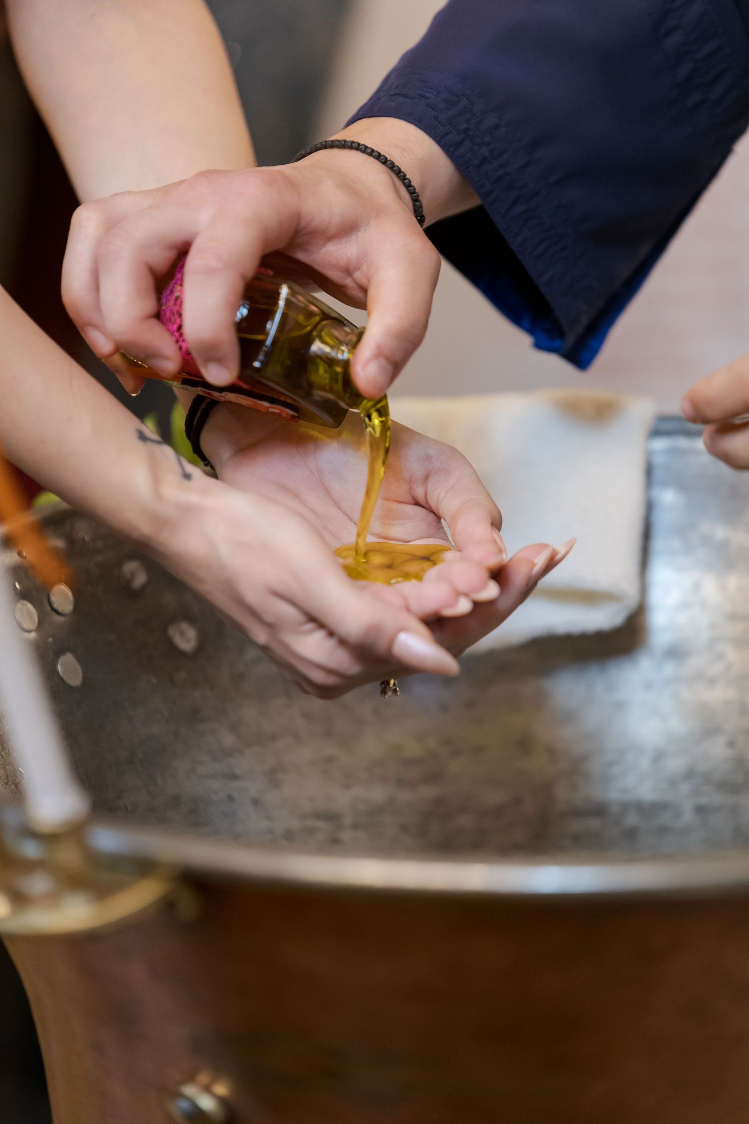 Hands pouring golden liquid into small vessels during a ceremony.