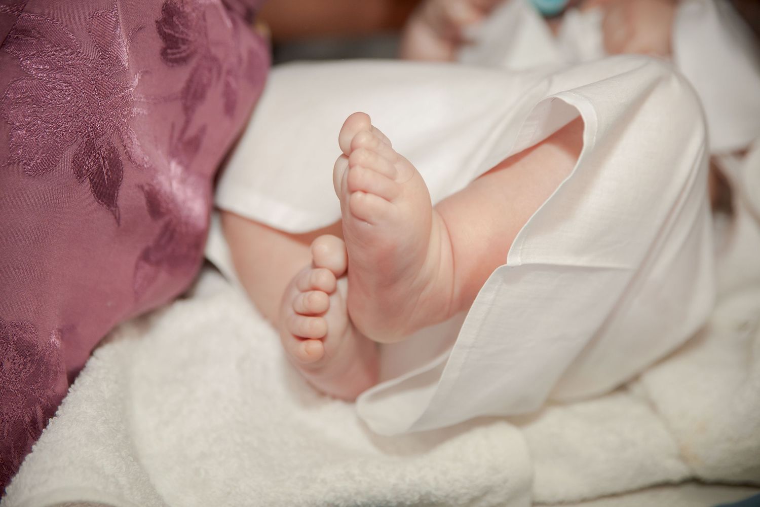 Close-up shot of tiny baby feet wrapped in soft white fabric.