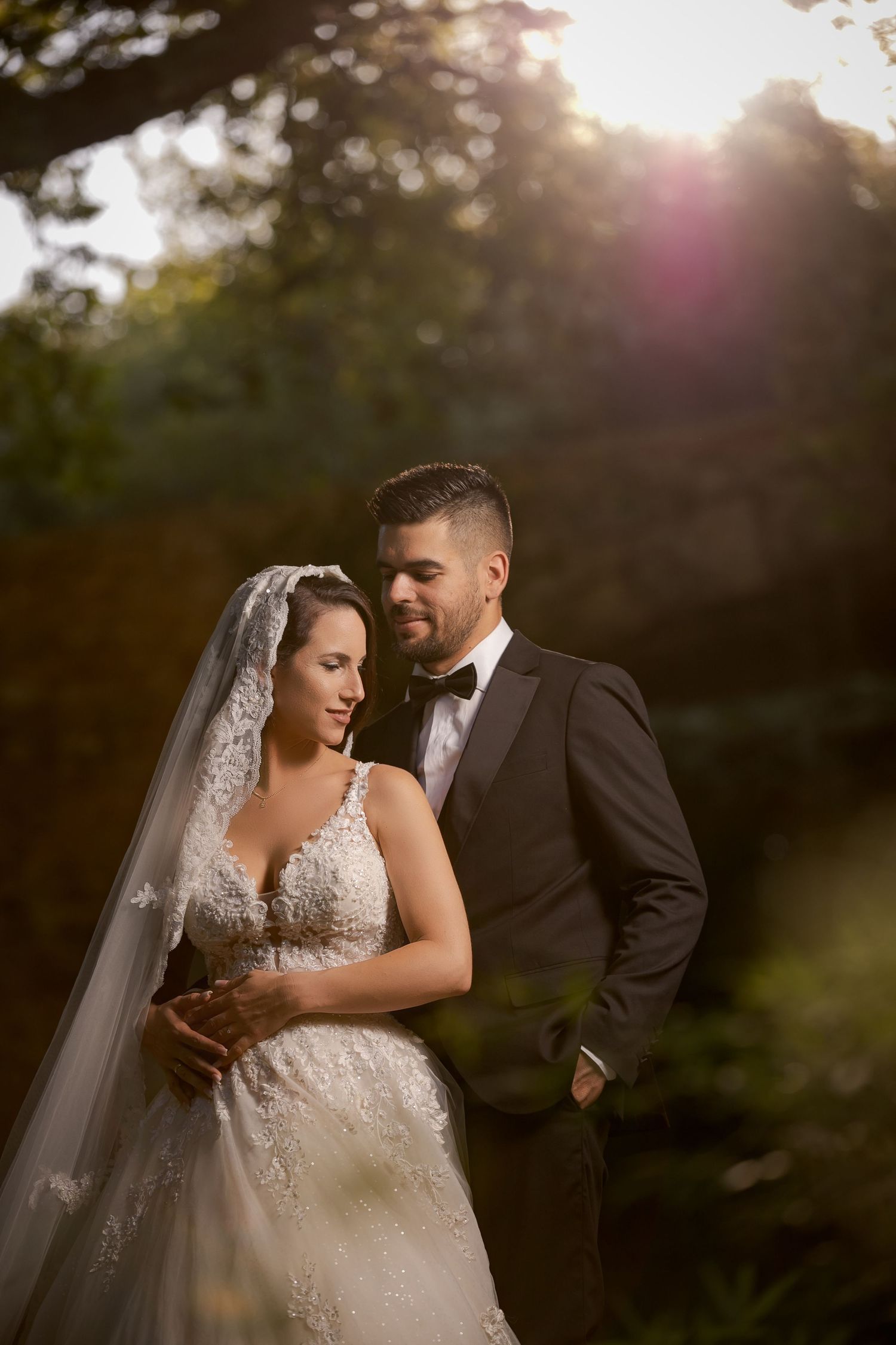 Romantic sunset wedding portraits in a natural outdoor setting with soft golden light filtering through trees.
