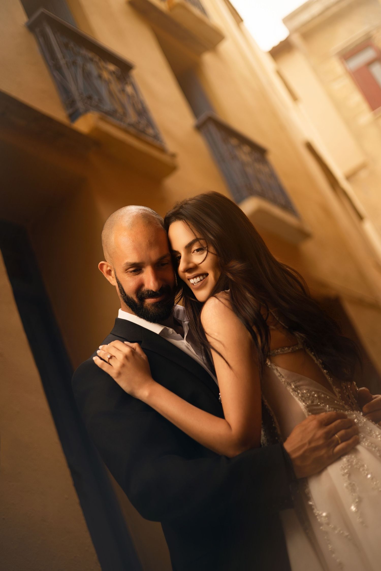 A romantic wedding couple sharing intimate moments in a softly lit hallway.