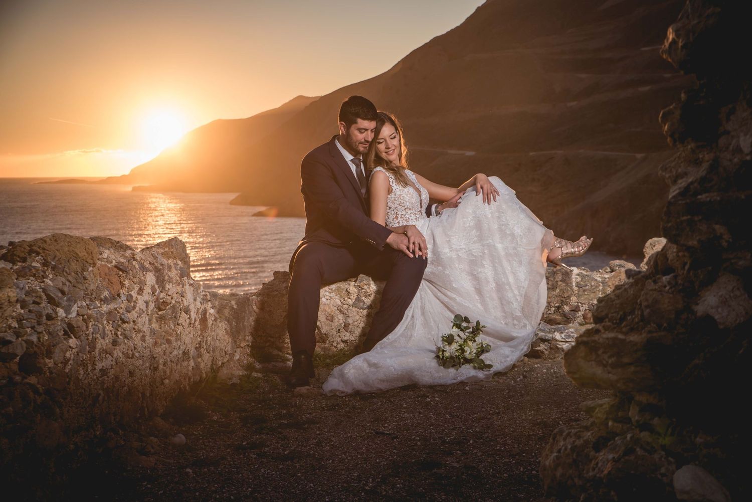 Sunset wedding photography session on dramatic rocky coastline with golden light.