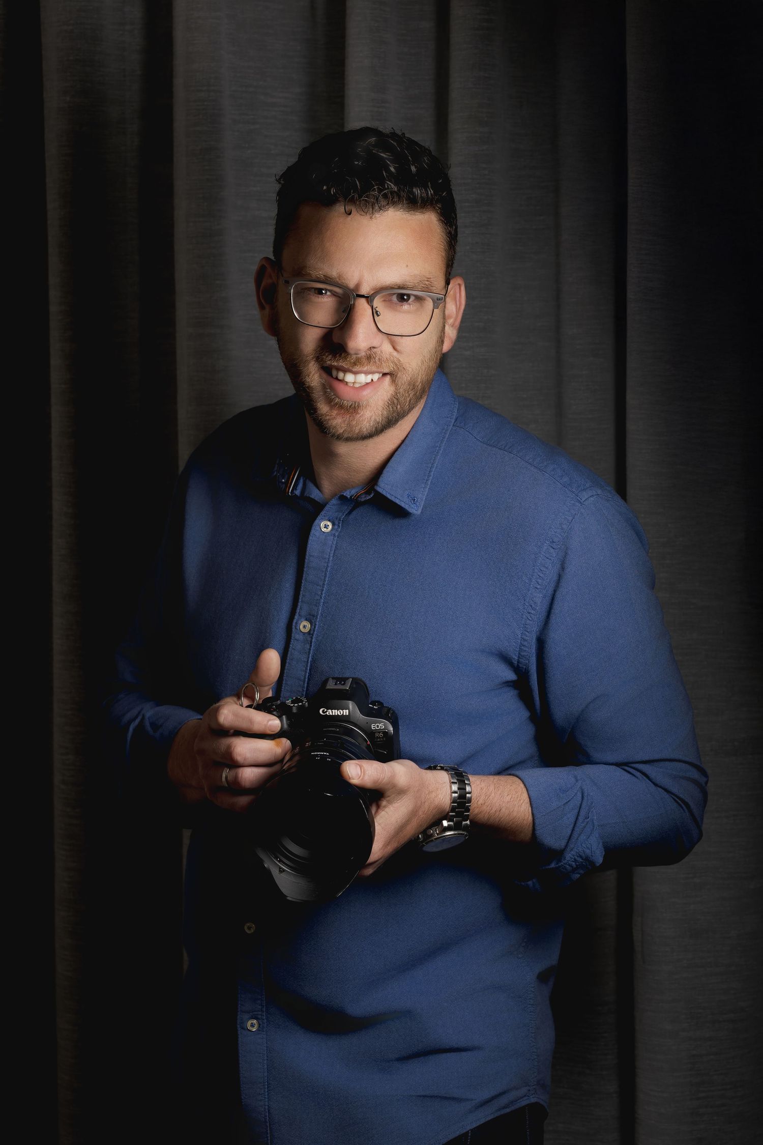 Studio portrait series showing photographer handling camera equipment in blue shirt and glasses.