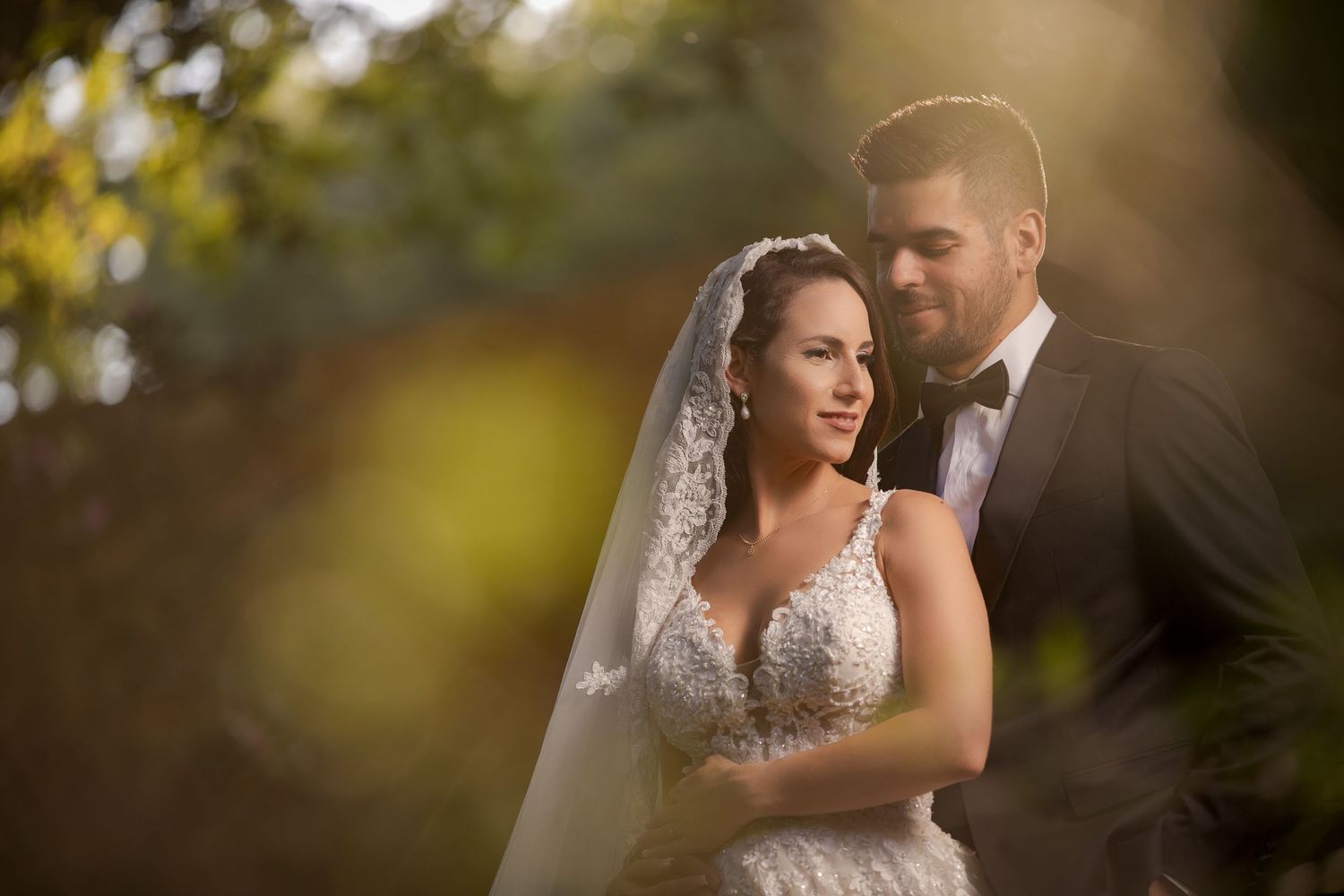 Intimate wedding photos captured through blurred foliage creating a dreamy bokeh effect.