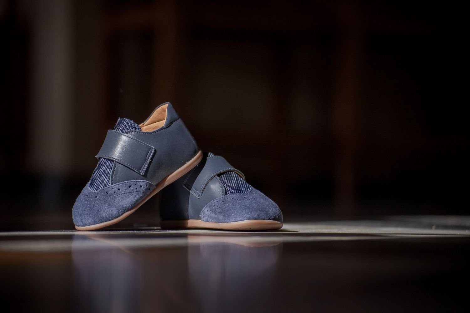 Elegant blue leather dress shoes placed on dark surface.