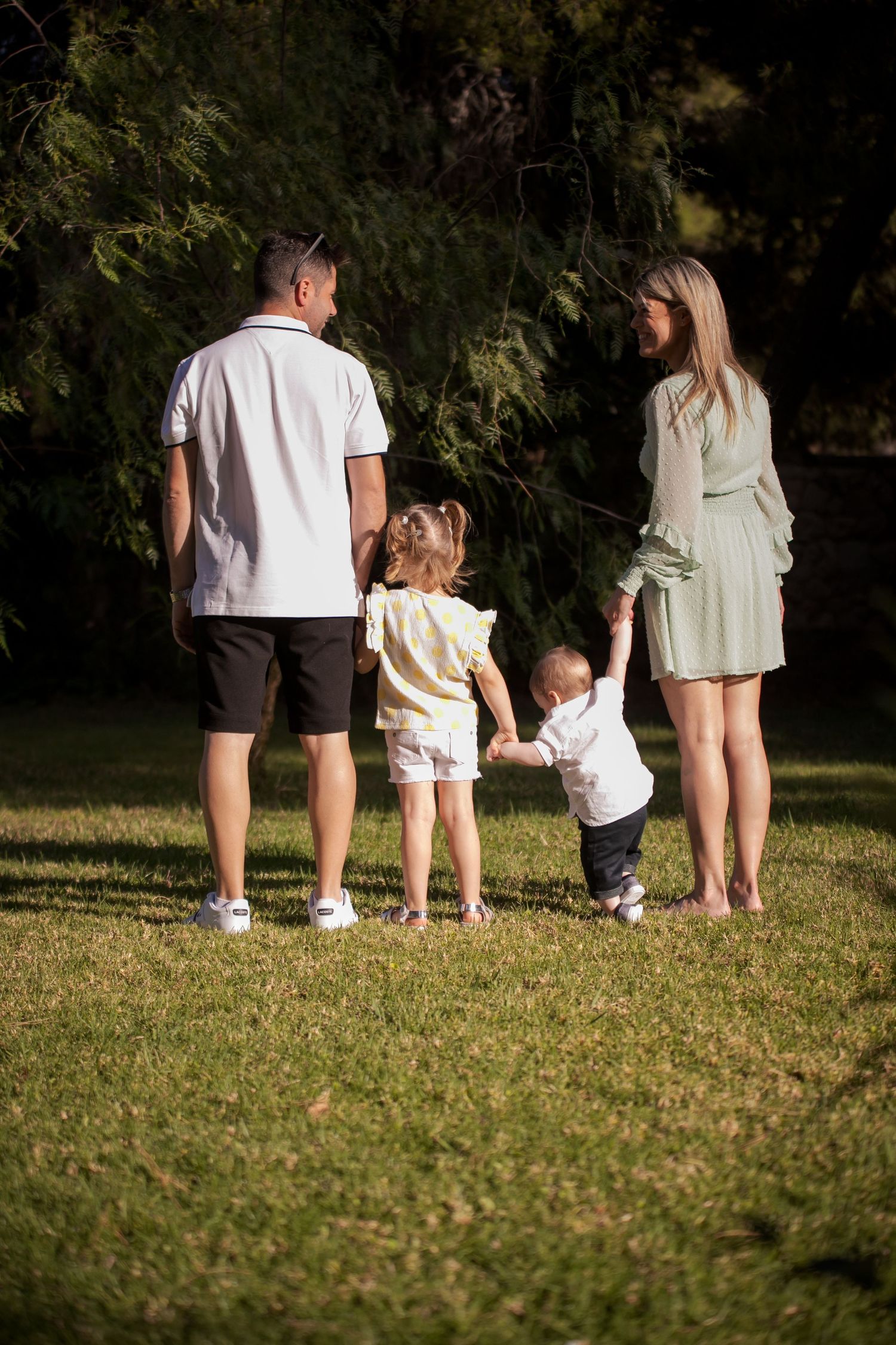 Family sitting together on grass during golden hour photography session.