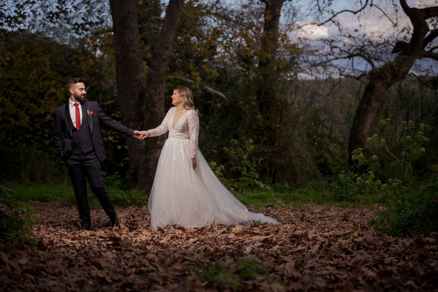 Autumn wedding photos showing couple walking through fallen leaves in natural setting.