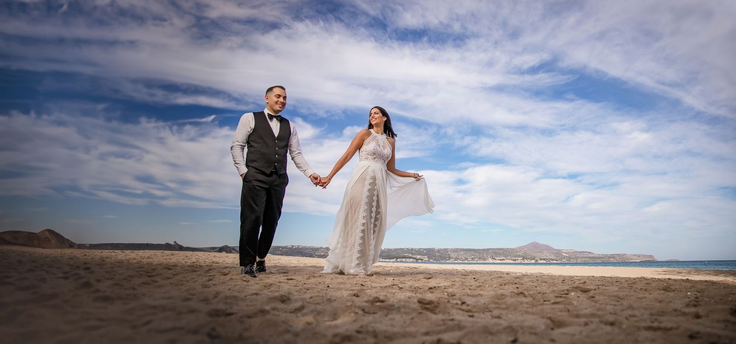 Panoramic beach wedding photography with dramatic cloudy sky backdrop.