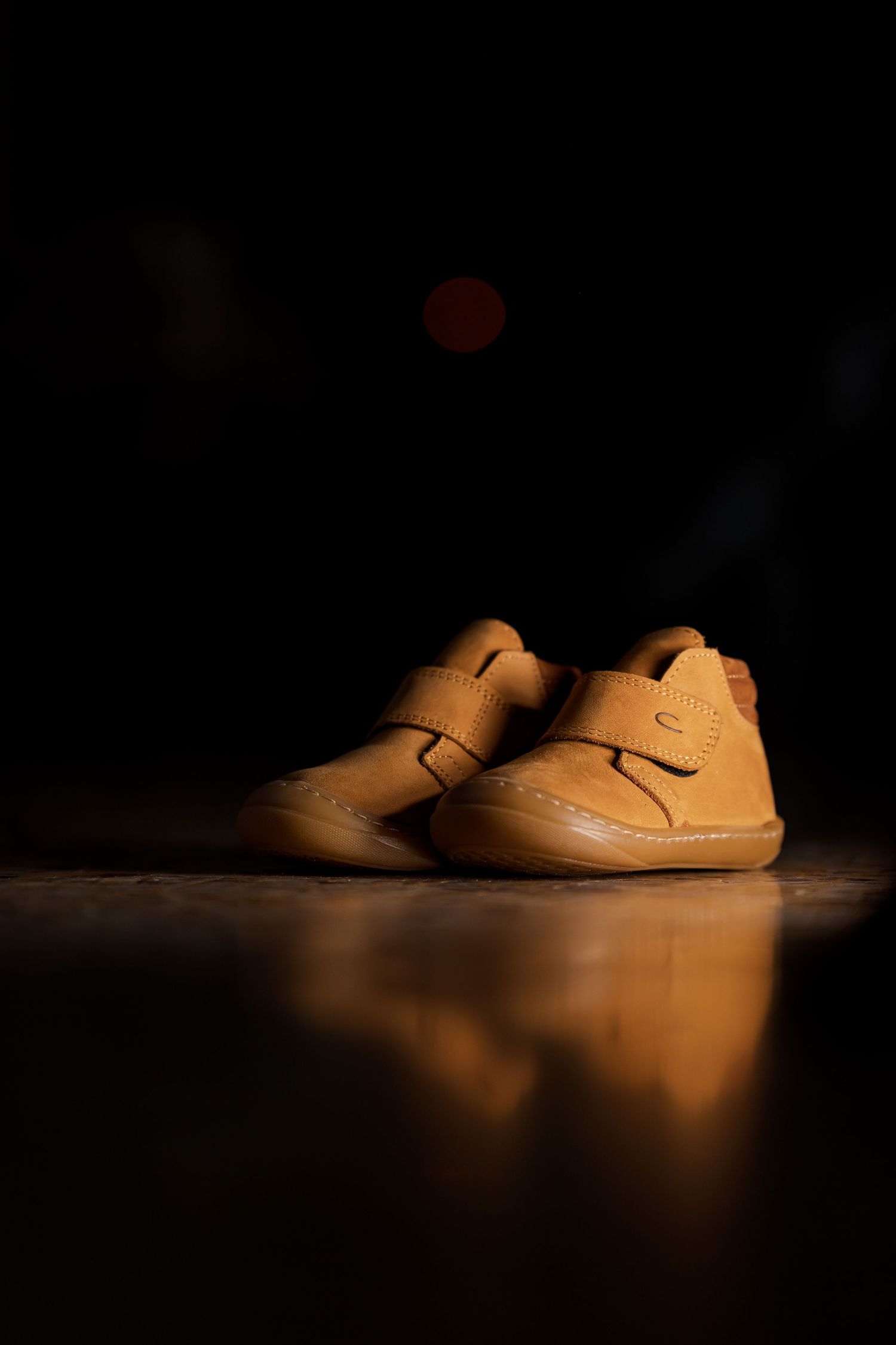 Minimalist product shot of tan children's shoes on white surface.