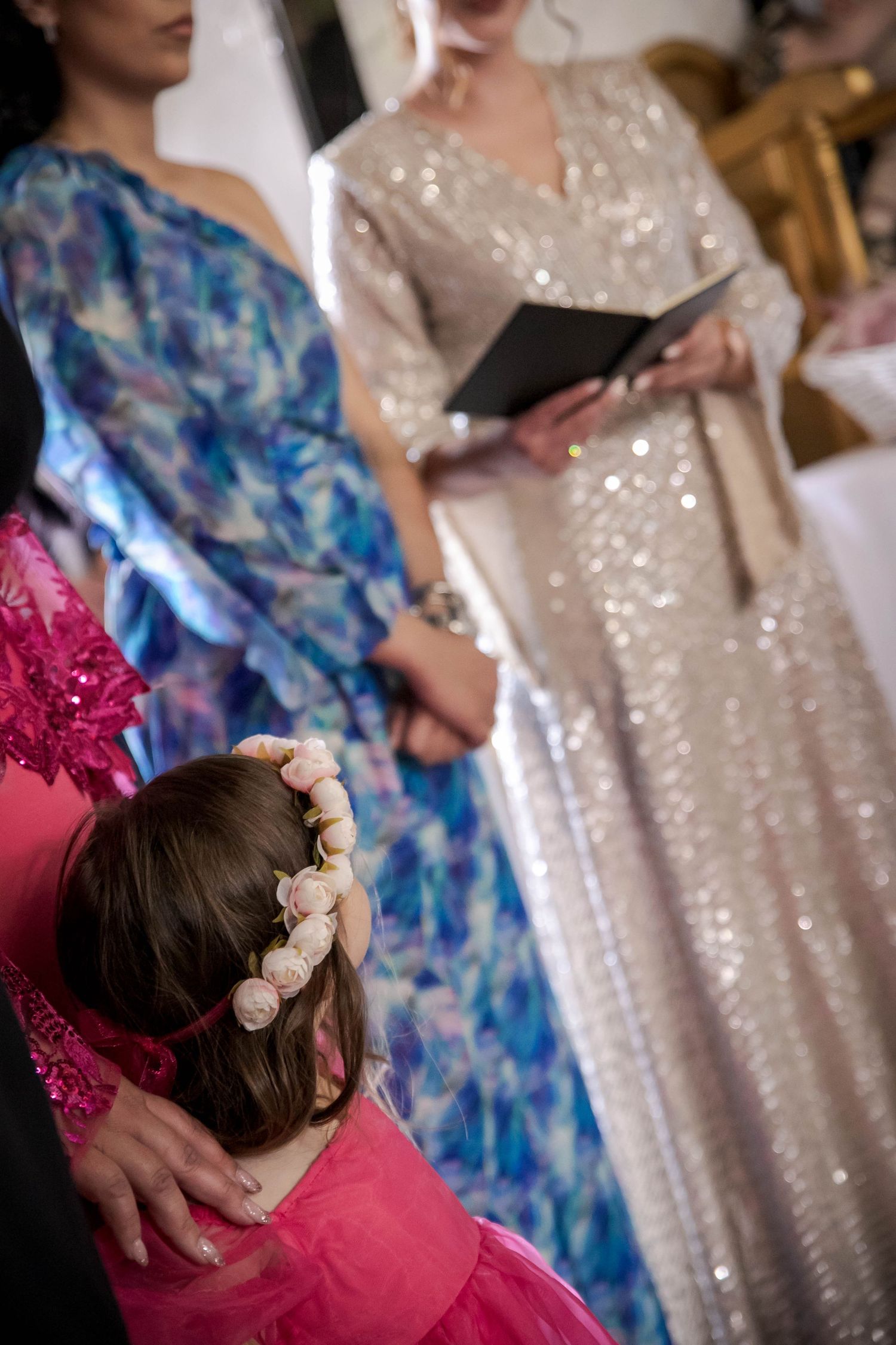 Detail shot showing a floral hair accessory against blue and pink formal attire at a wedding event.